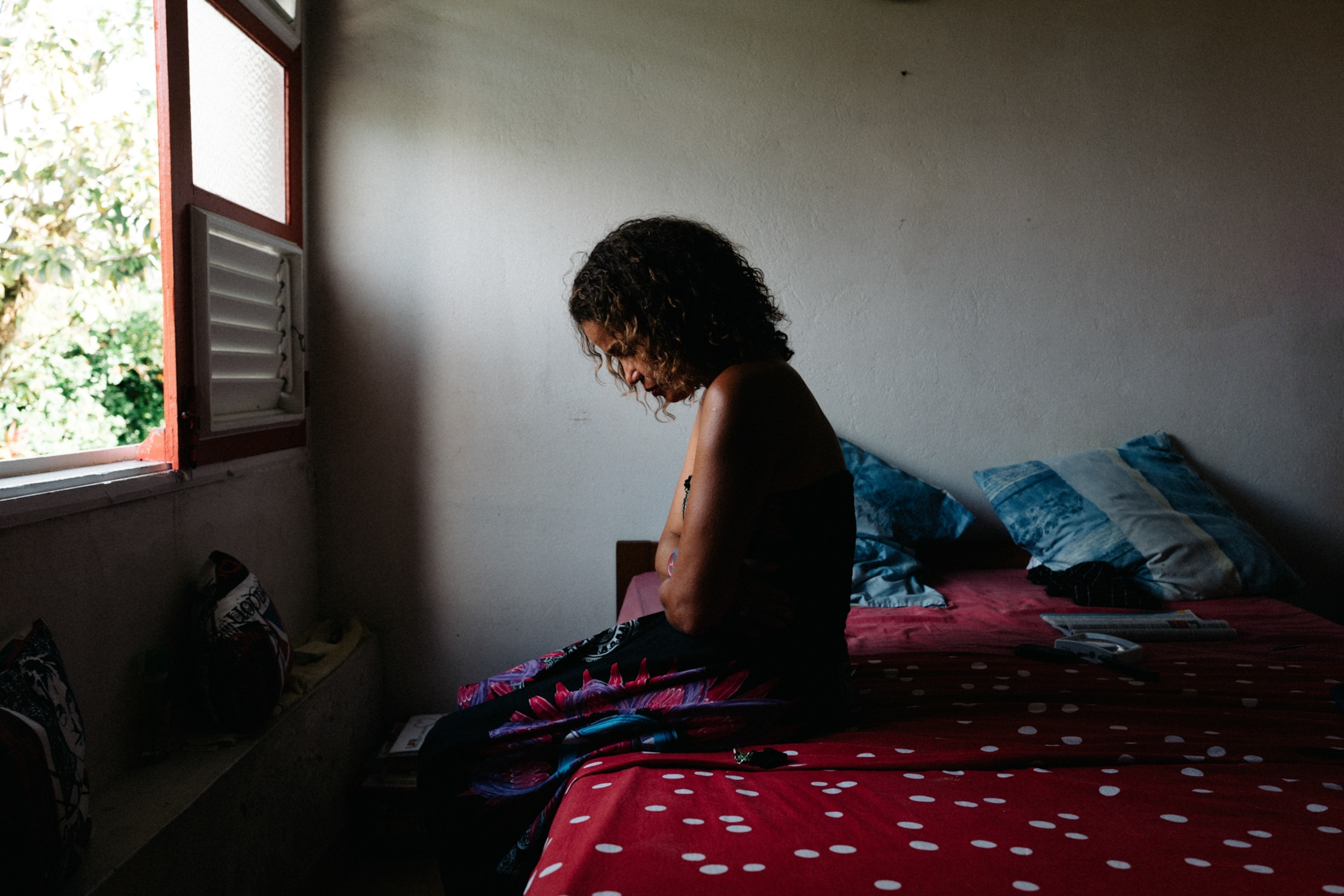 A woman with endometriosis sits in bed holding her belly.