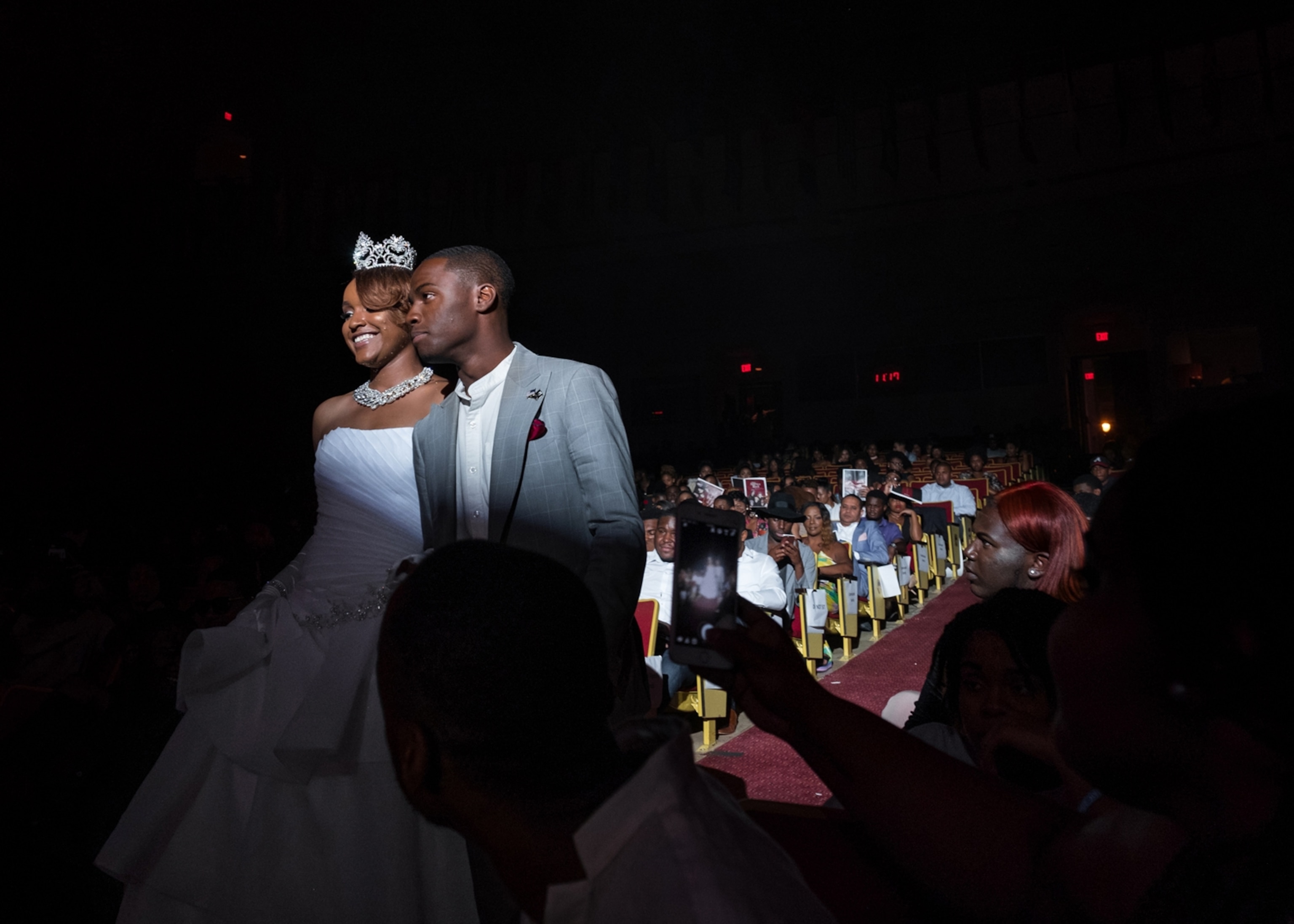 a couple of young black students she is wearing a white gown and tiara he a gray suit