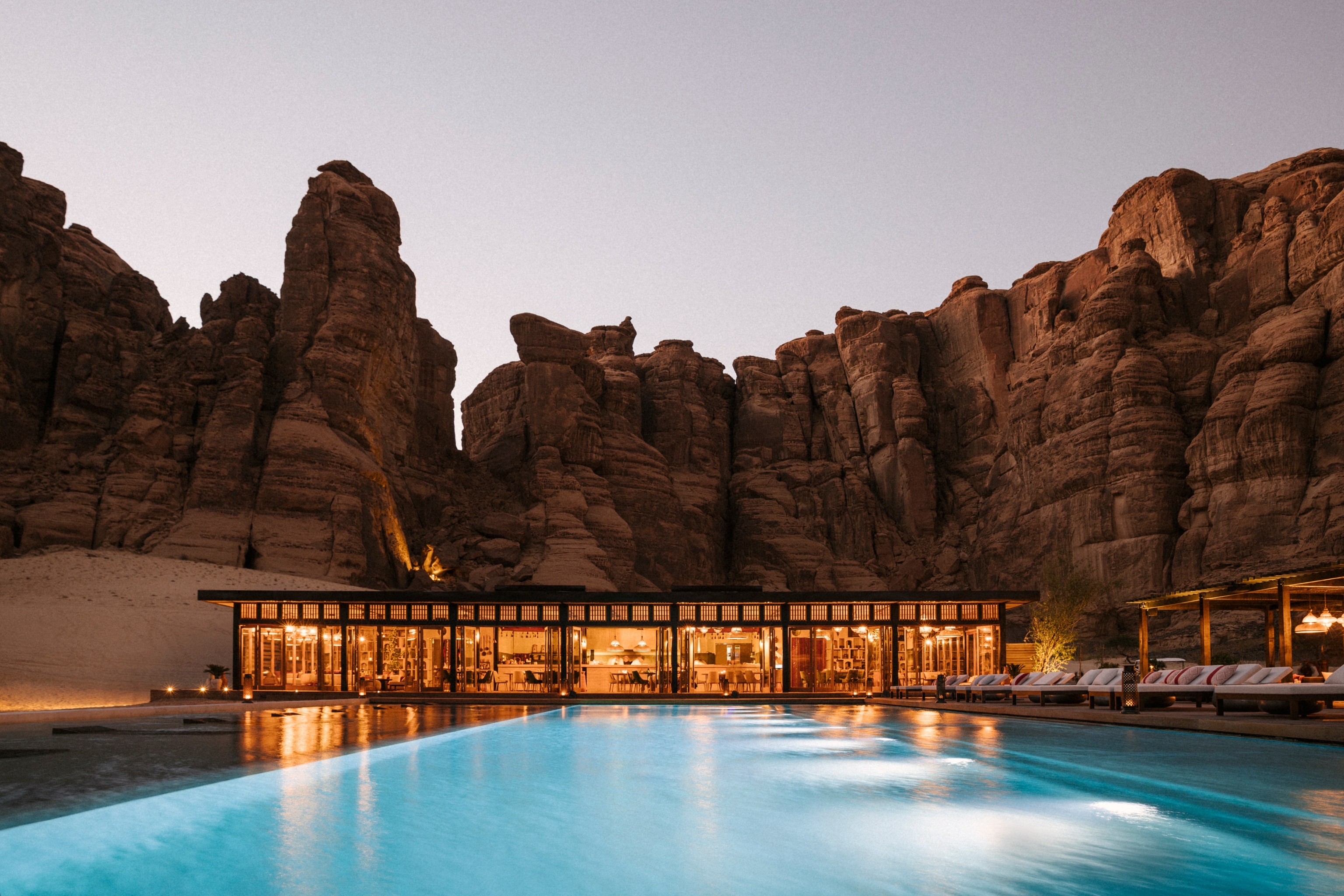 A view of the pool at the Habitas AlUla hotel at dusk