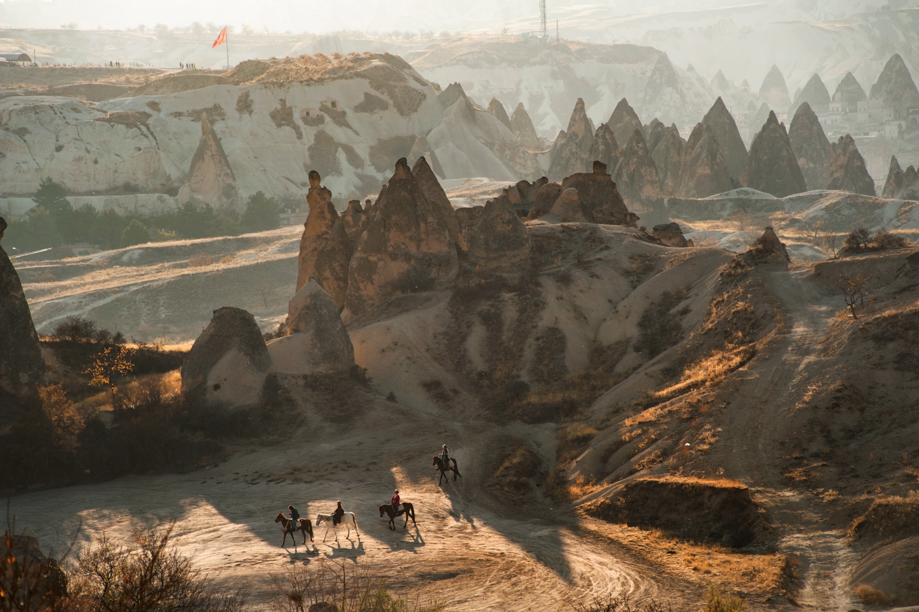 A group of people on horseback are seen as they walk through the valleys formed by dozens of peaks in the volcanic landscape.