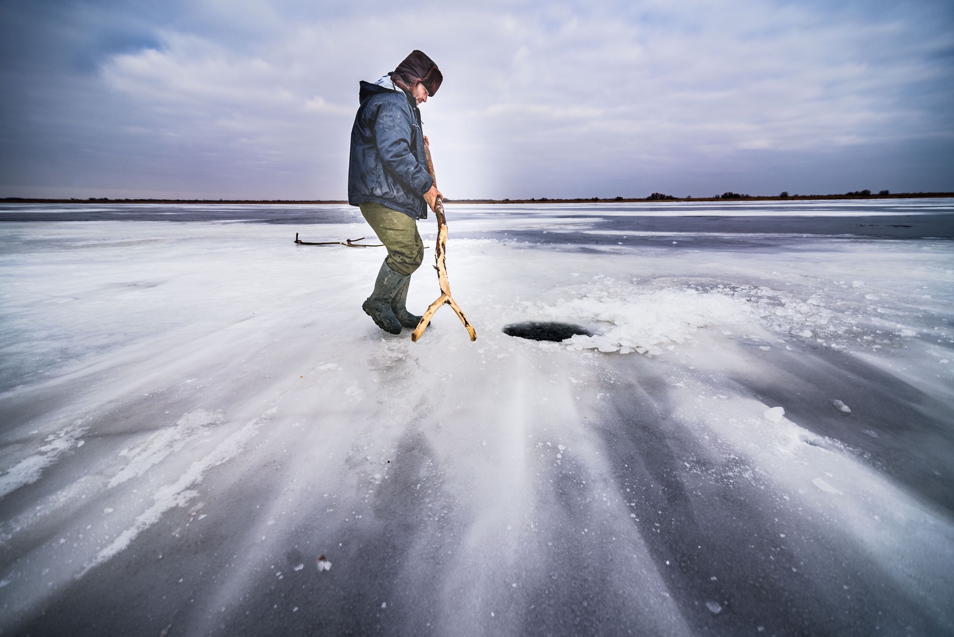 ice fisherman on frozen Lake Gorgova in Romania