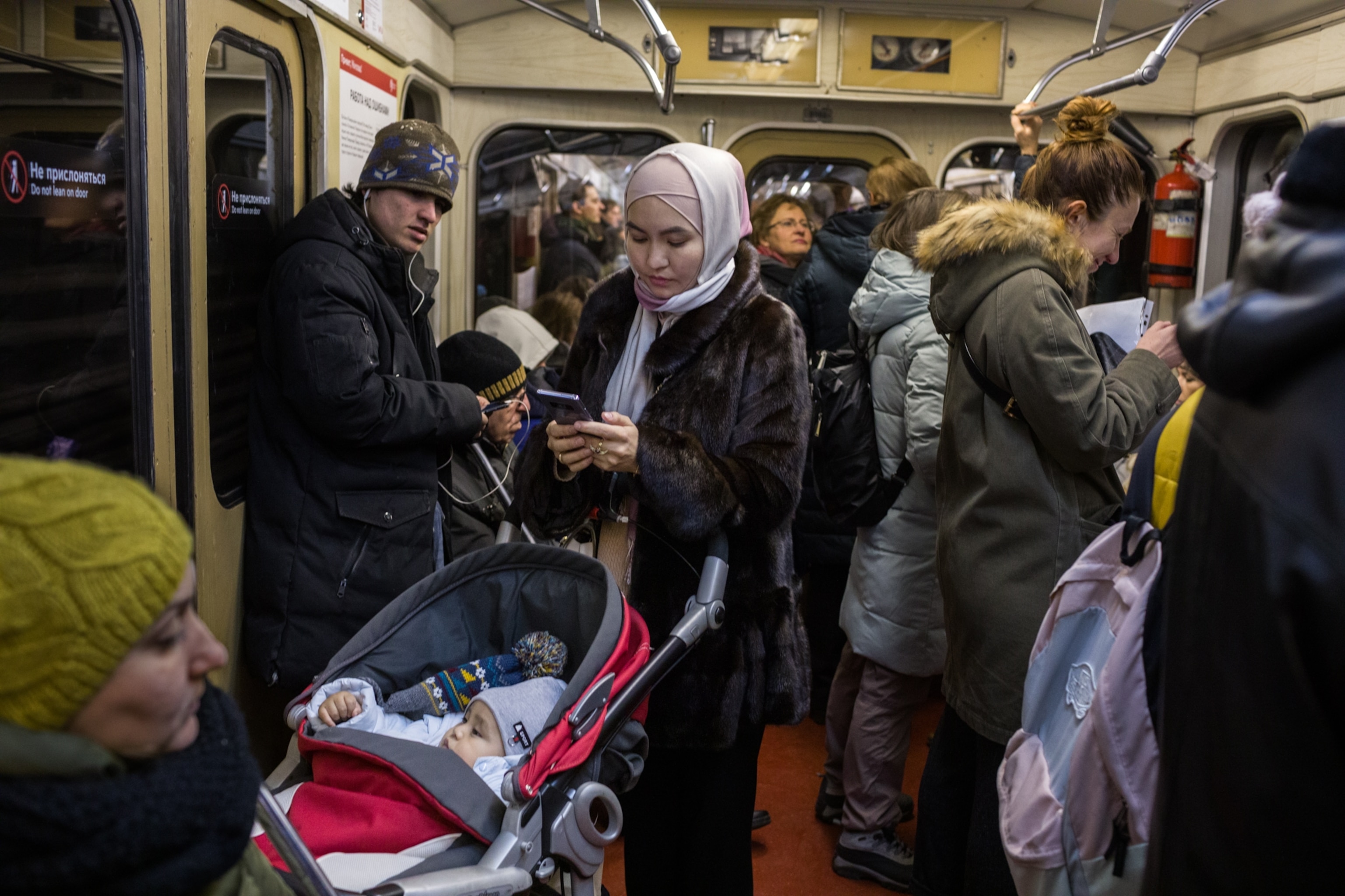 a woman on a busy train with a stroller and a baby