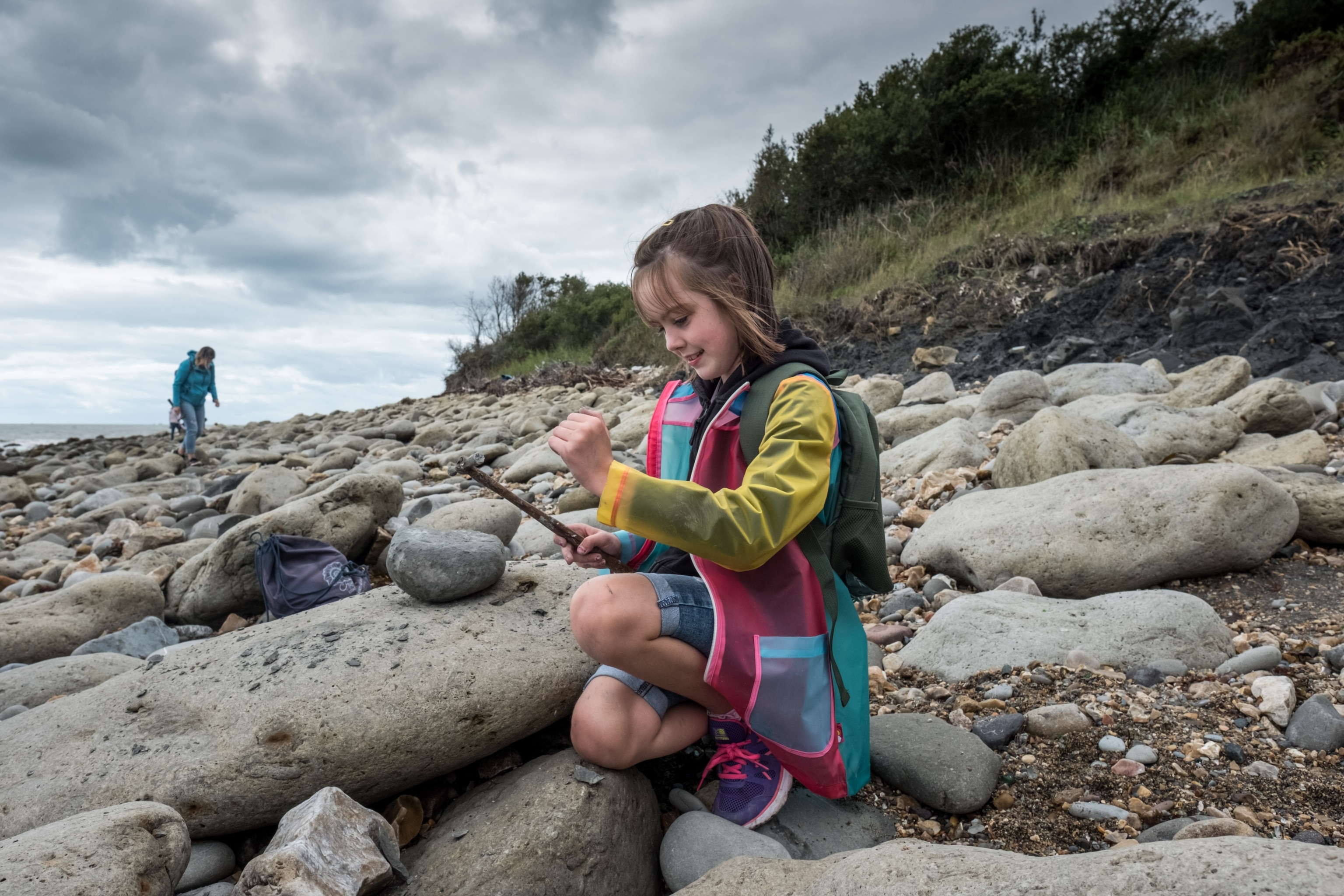 a young girl examining a fossil she just discovered on the beach