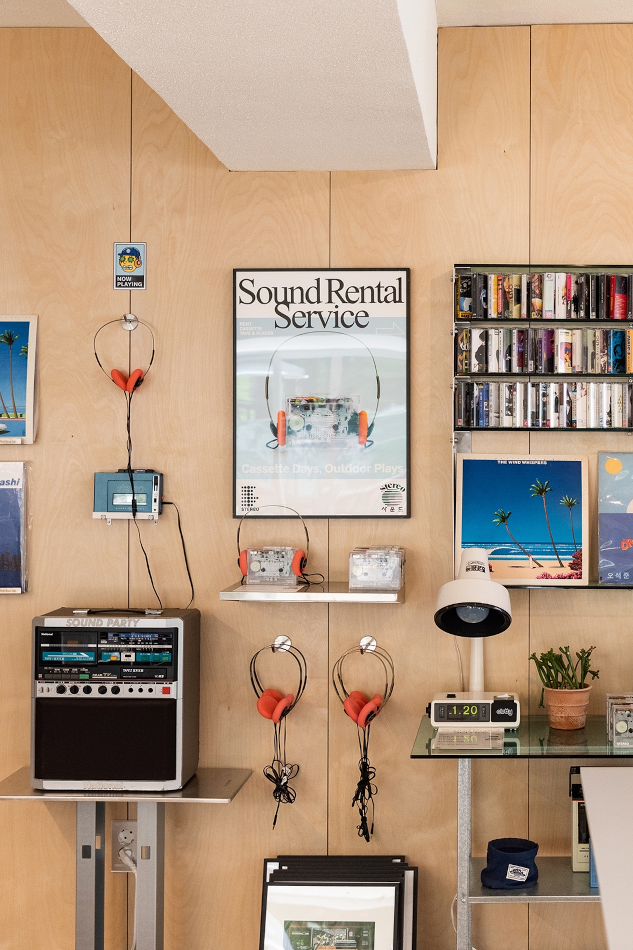 Headphones and sound systems hung on a wall with a poster reading 'Sound Rental Service'
