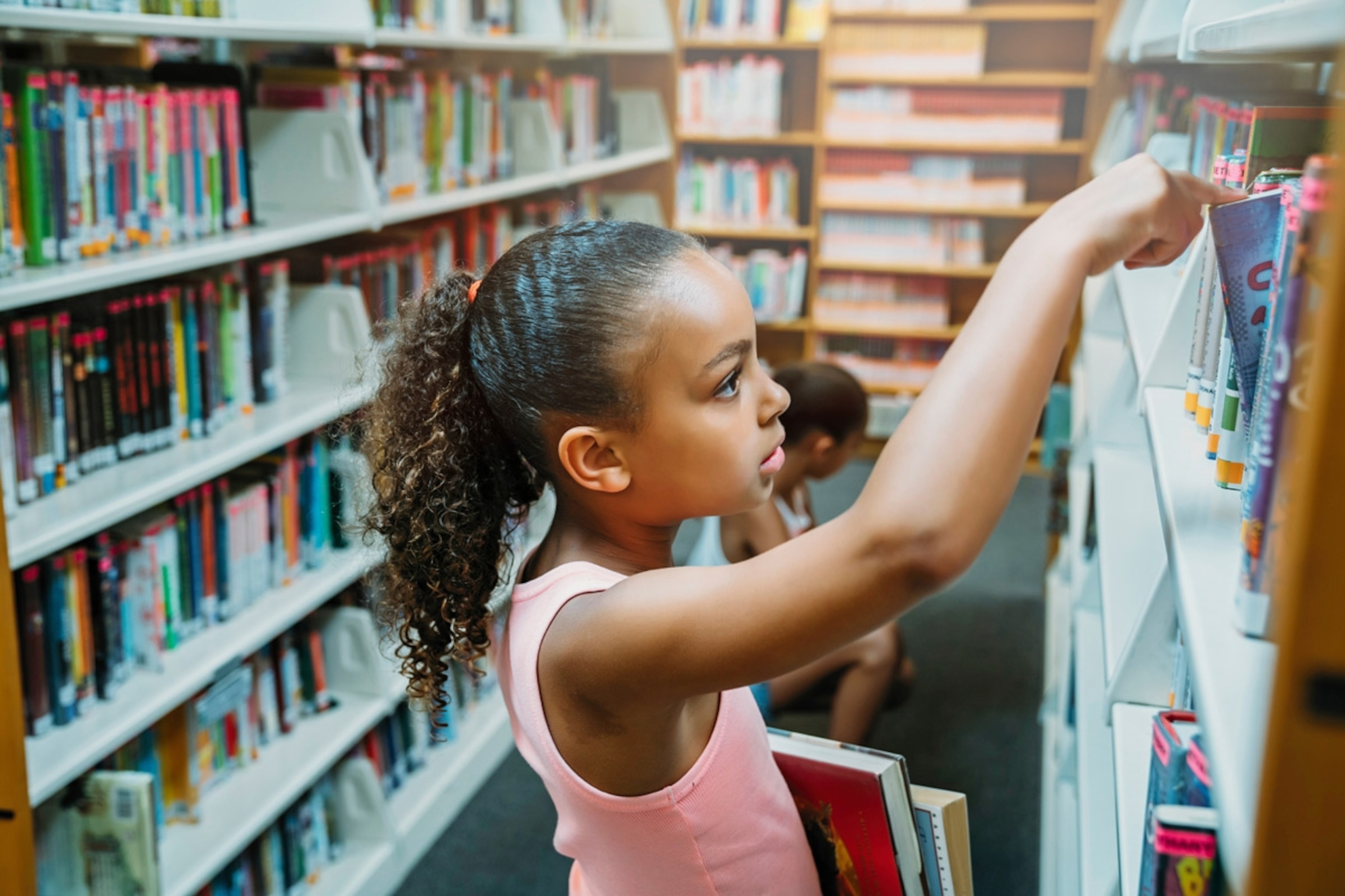 Girls looking at books in public library.