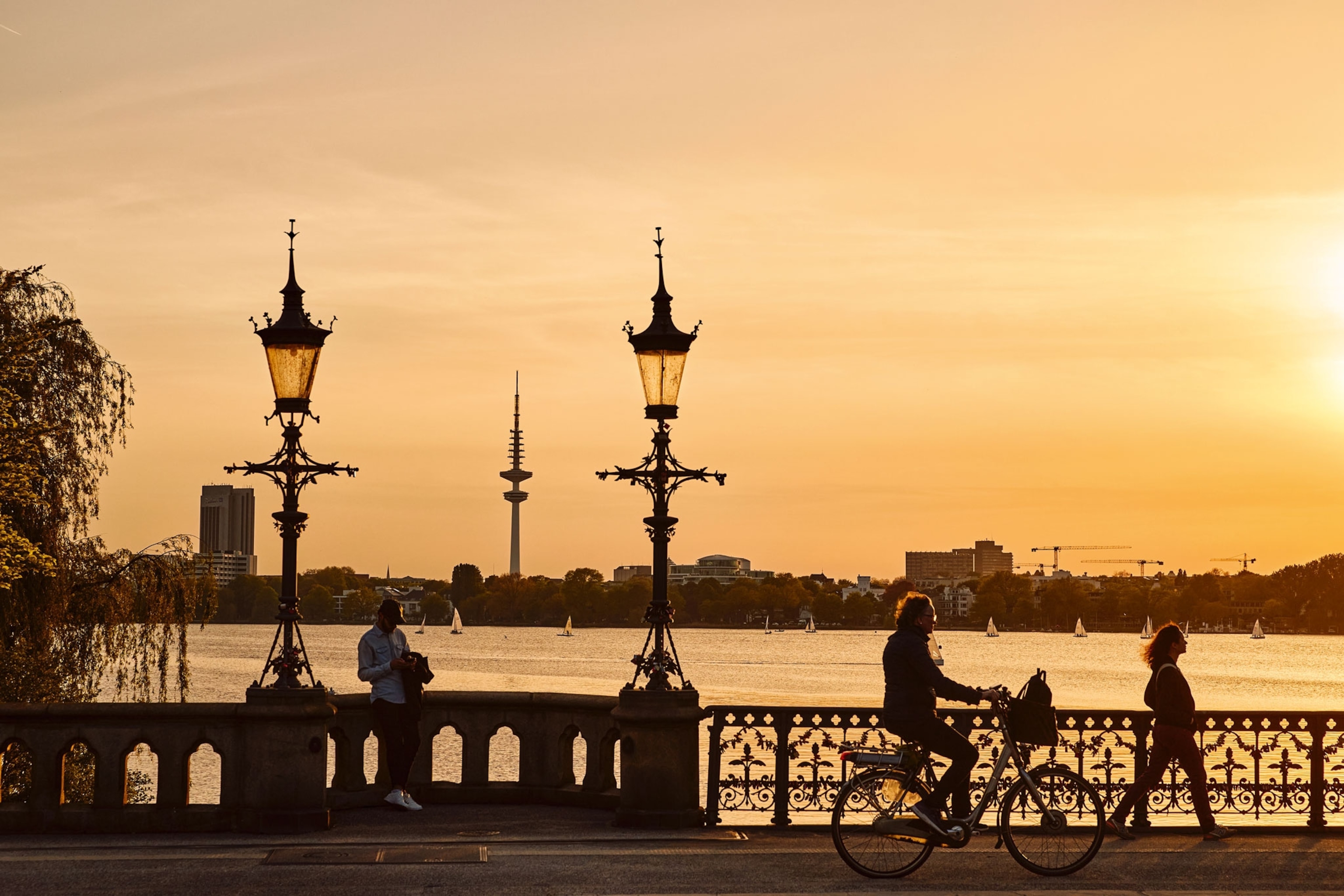 People walk and cycle across a bridge over a lake.