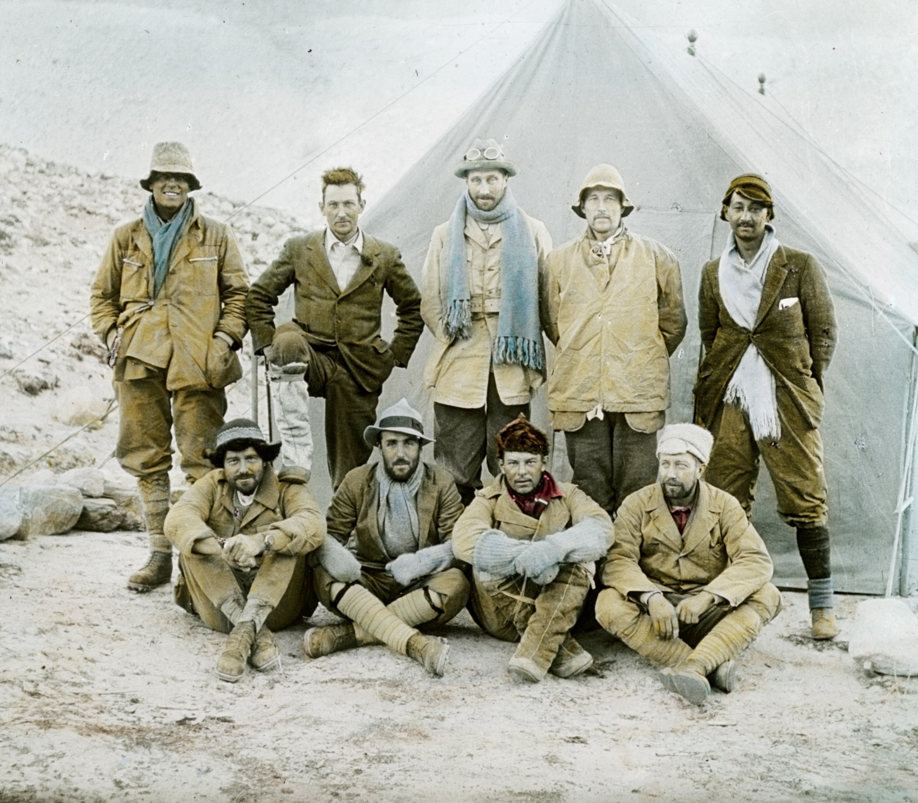 nine men, four sitting in front of five standing, posing for the camera