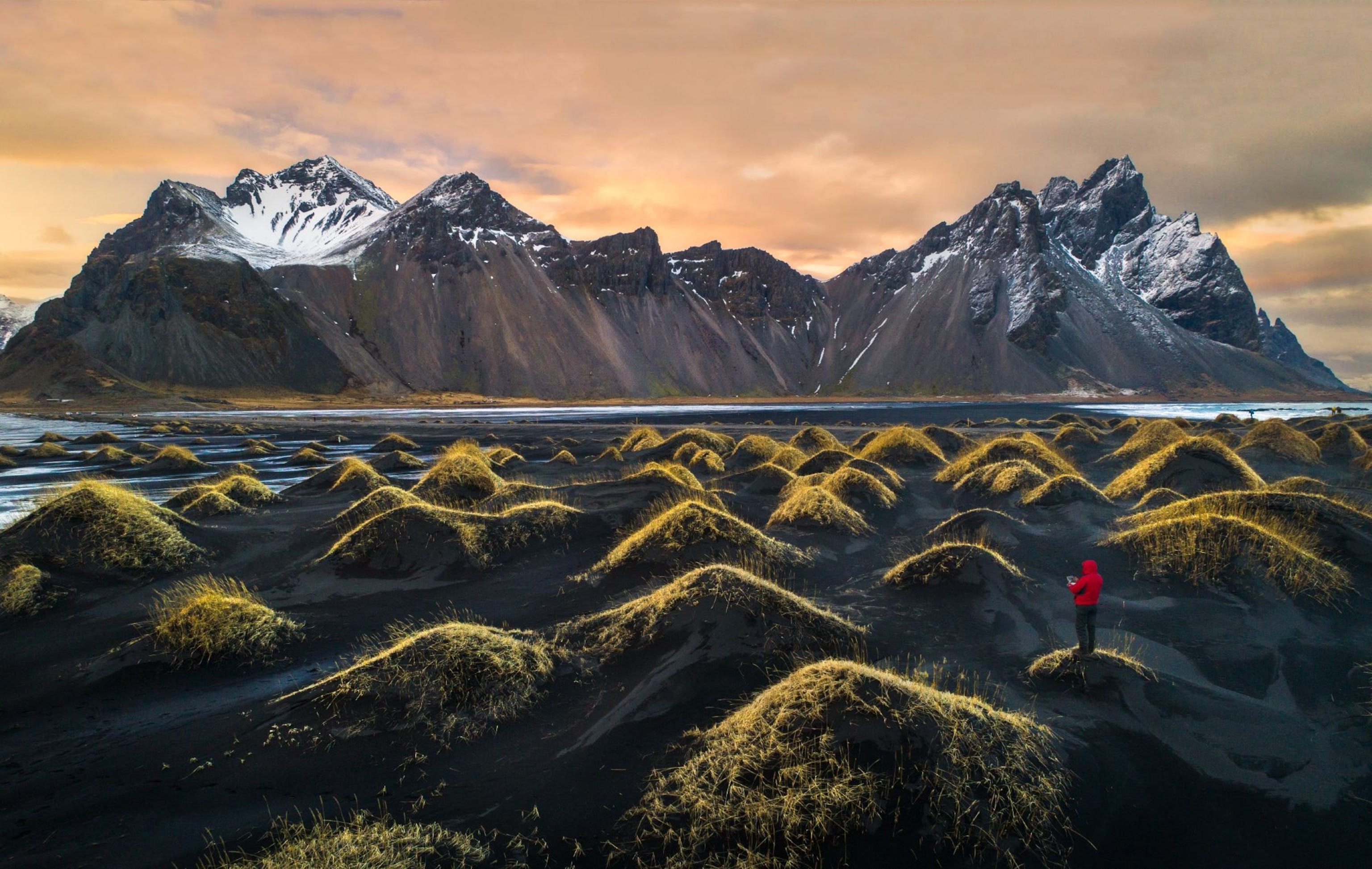 a hiker near mountains in Vestrahorn, Iceland