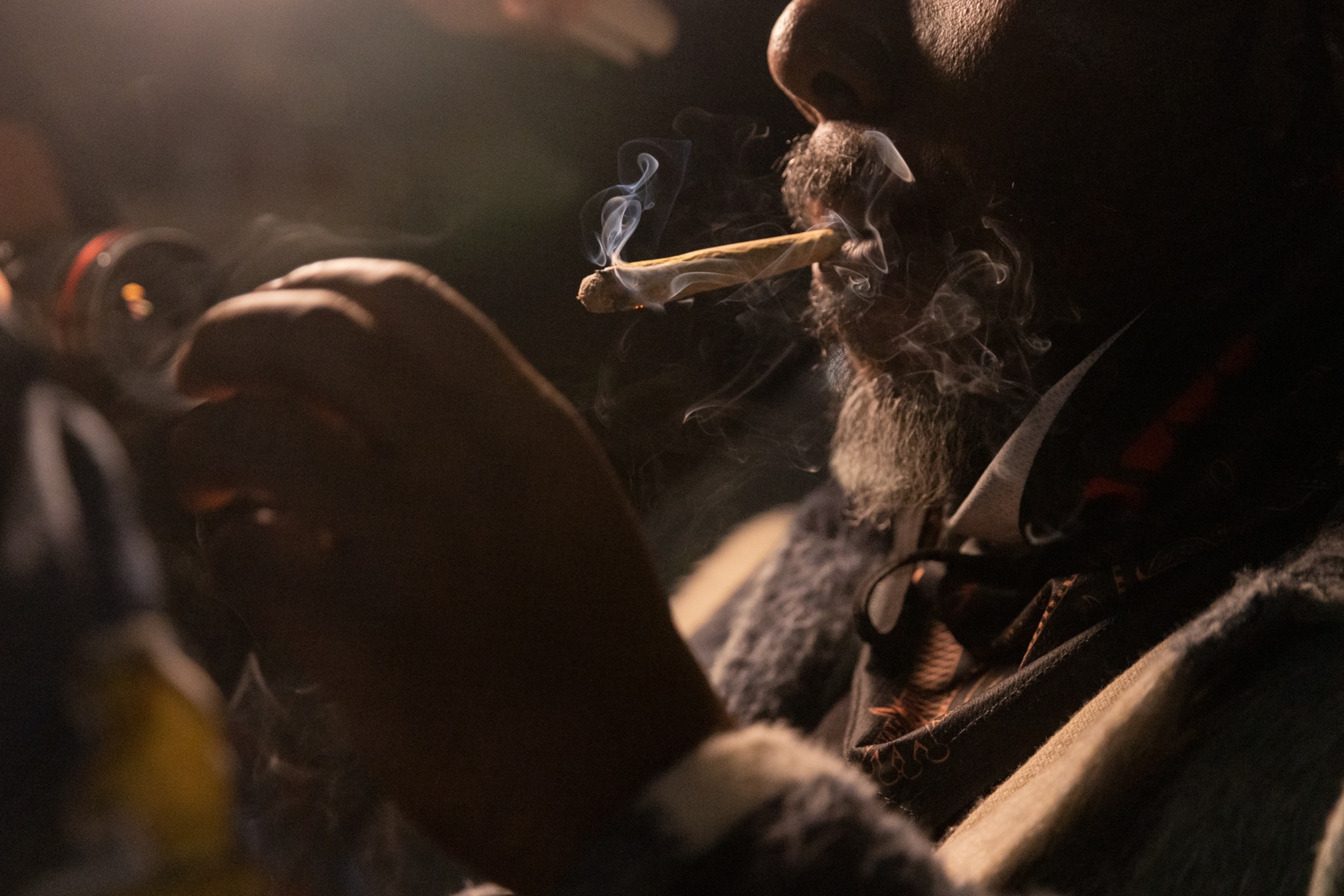 A close up of a bearded man smoking a joint.