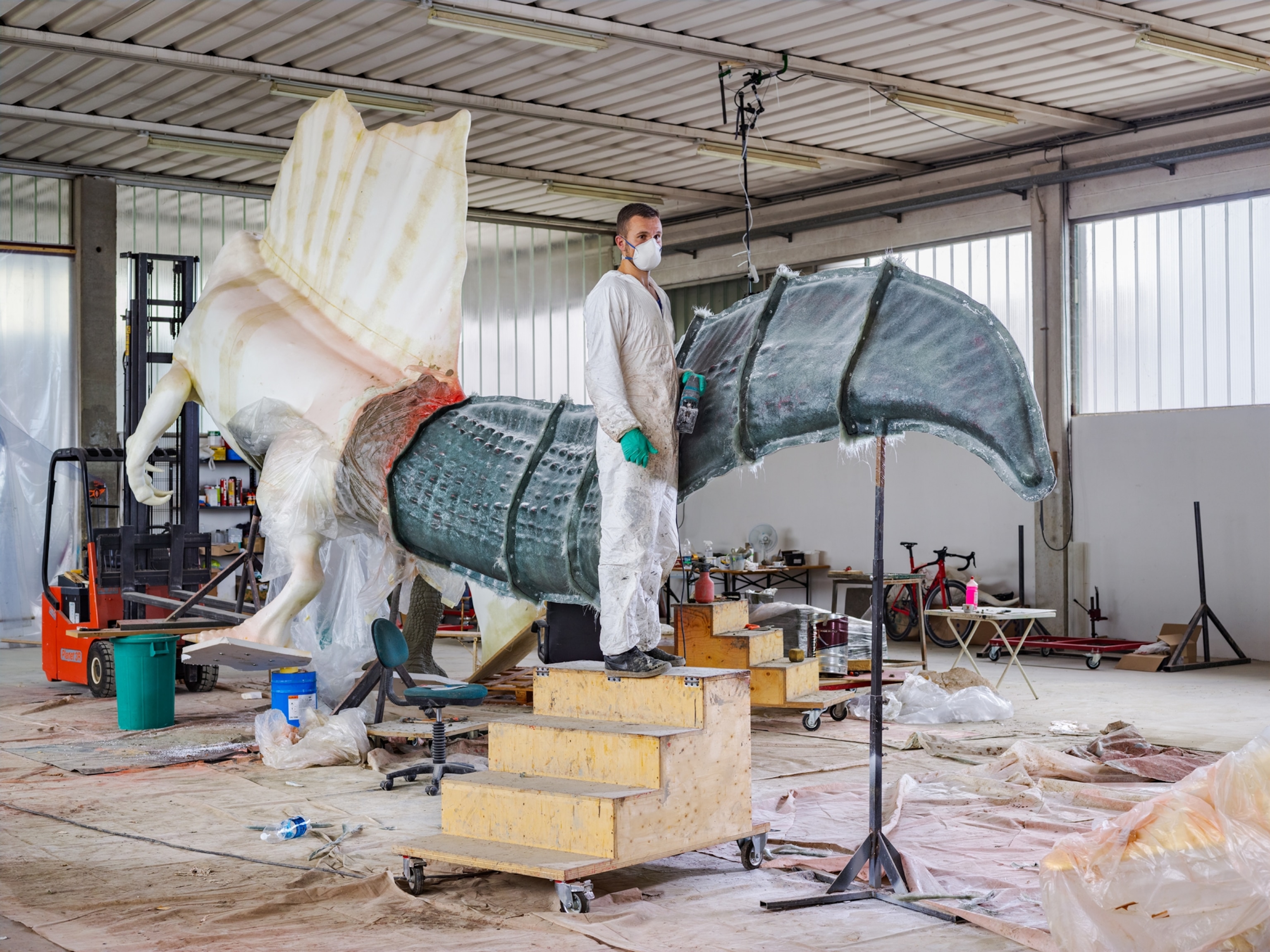 a man standing on a stoop next to a working dinosaur sculpture