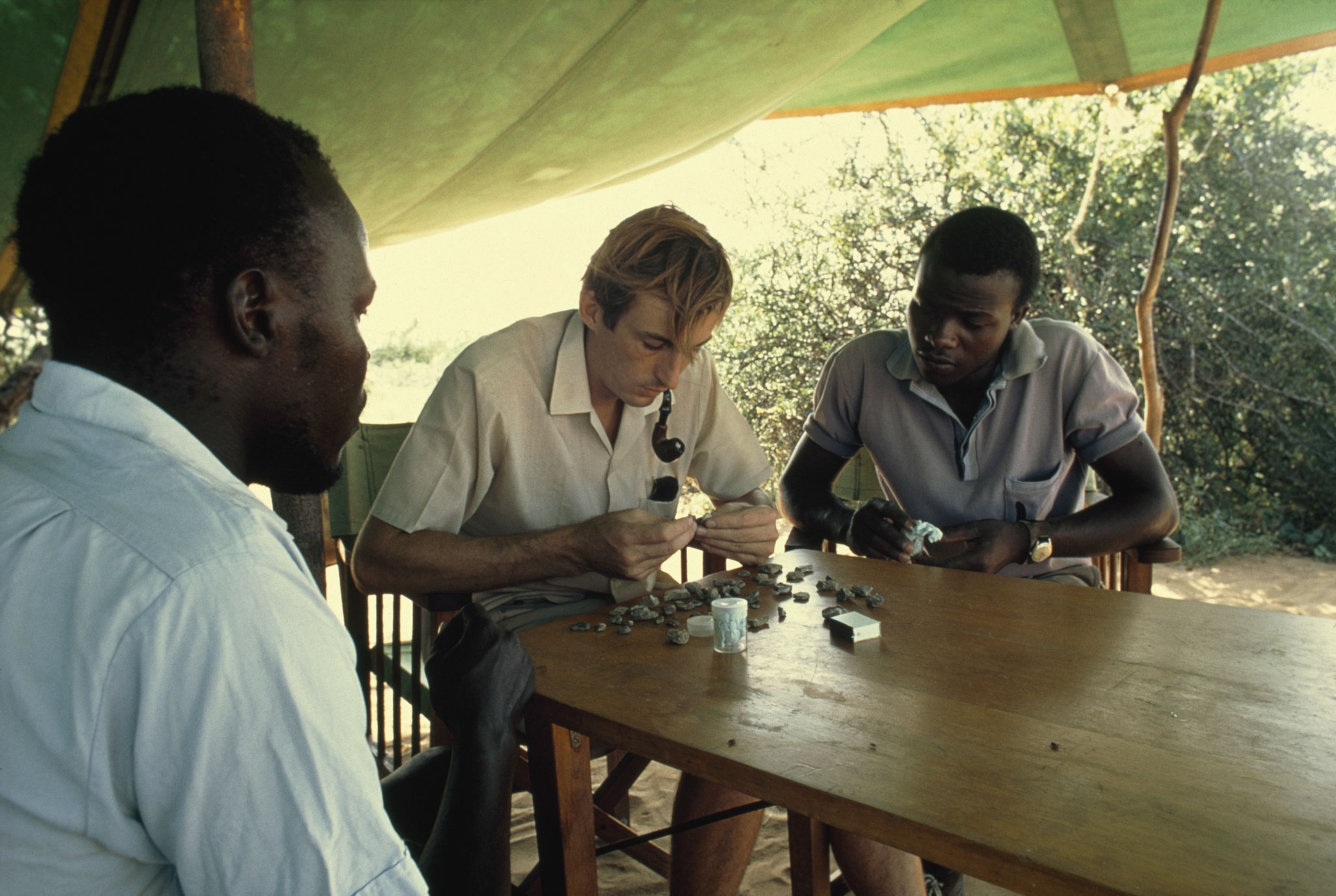 Richard Leakey packs fragments of a prehistoric skull with two men