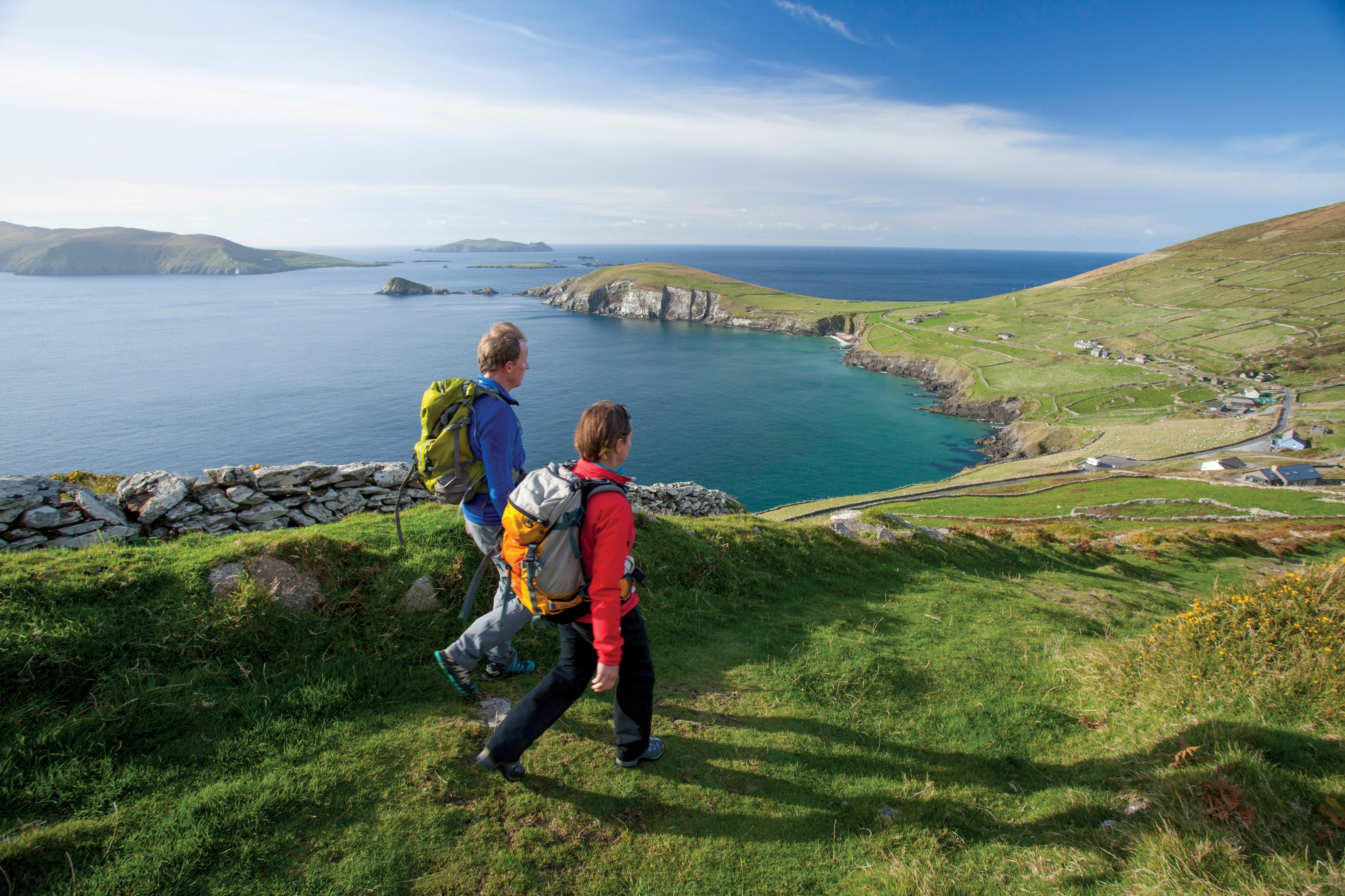 A middle-aged couple of hikers walking along the coast of Dingle Peninsula in Ireland.