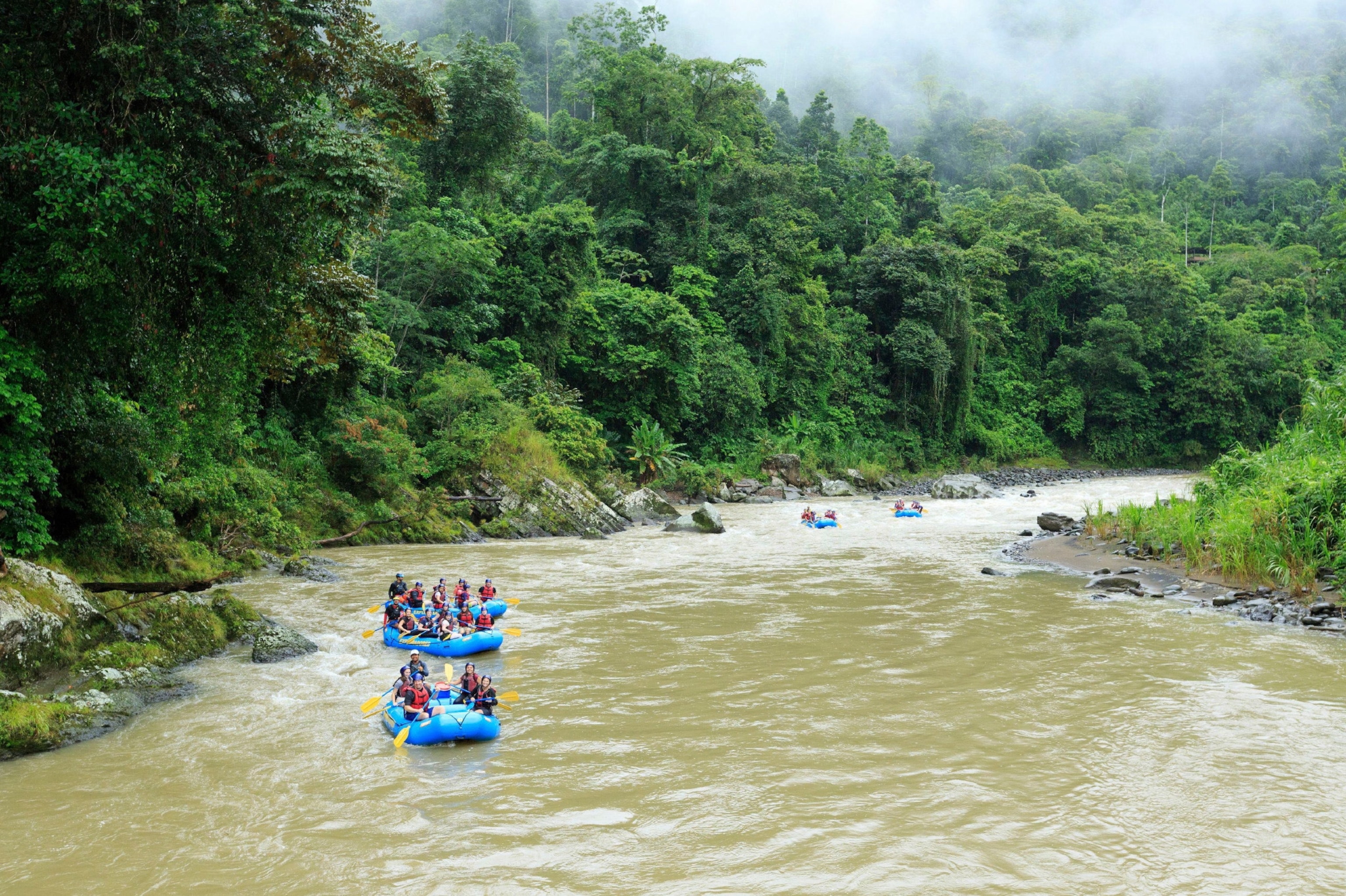 Rafts of people float down a river in the Rio Pacuare Valley