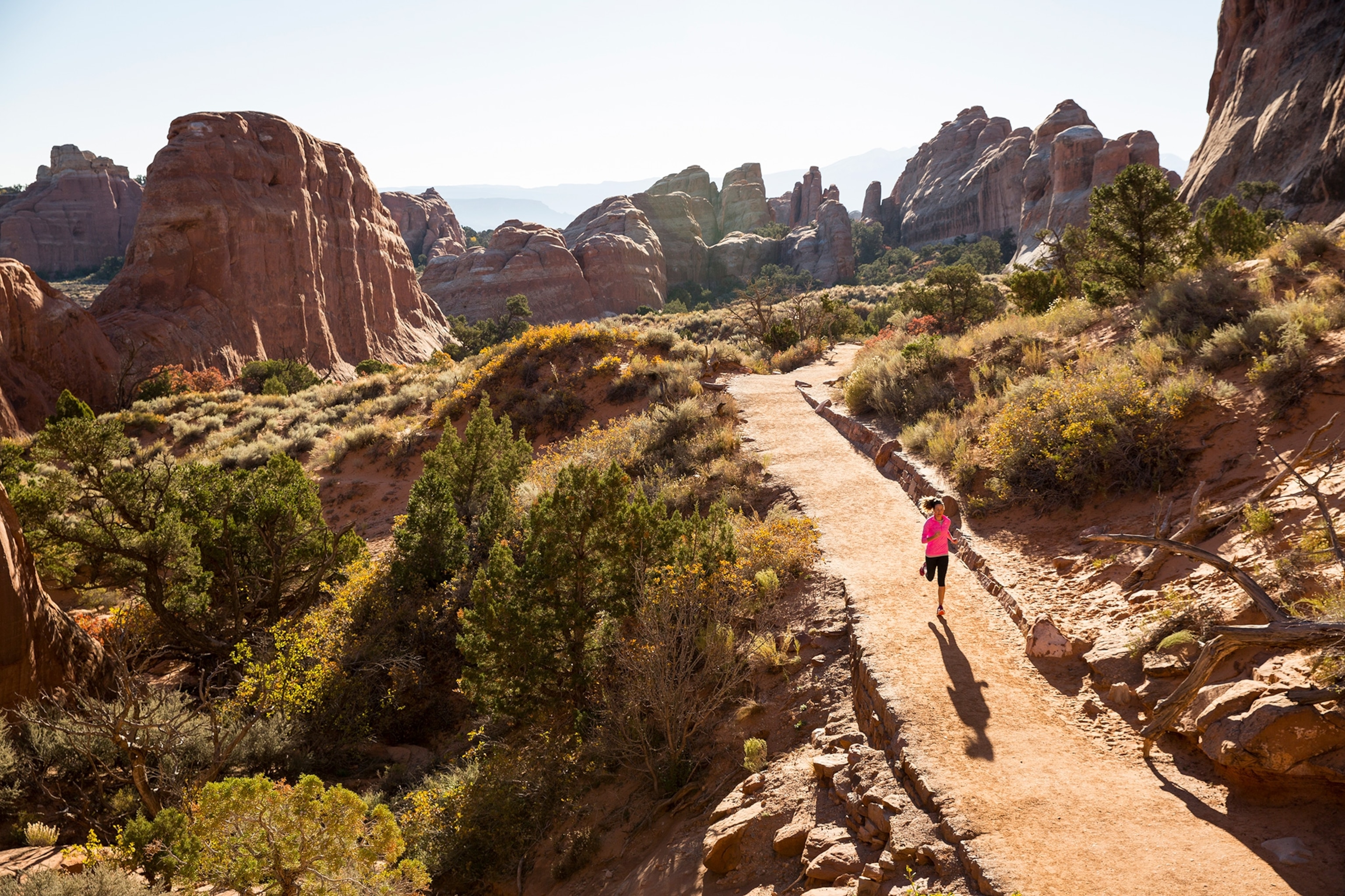 A woman trail running in Arches National Park.