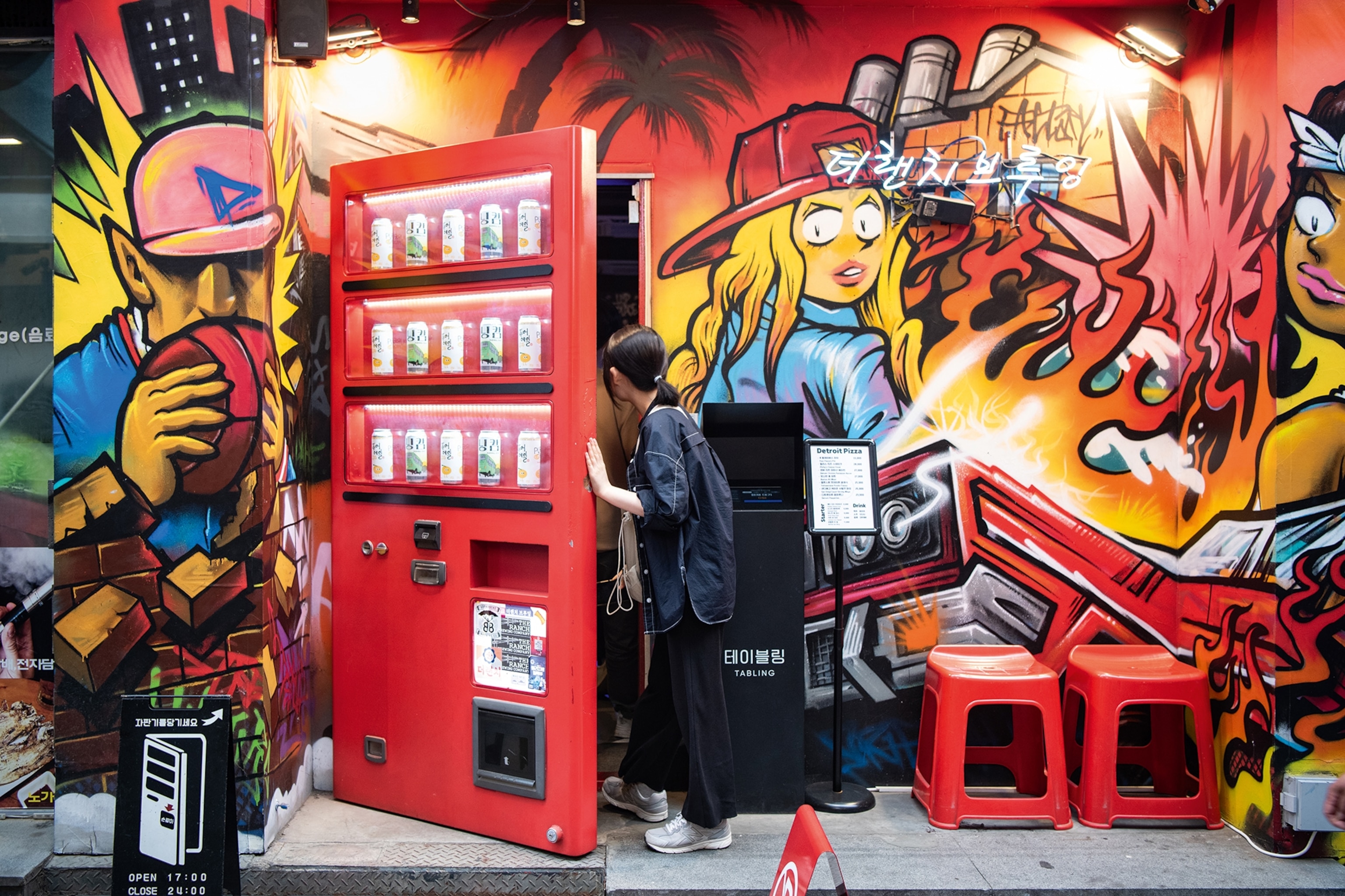 Woman opening a door fixed into a wall painted with animated figures