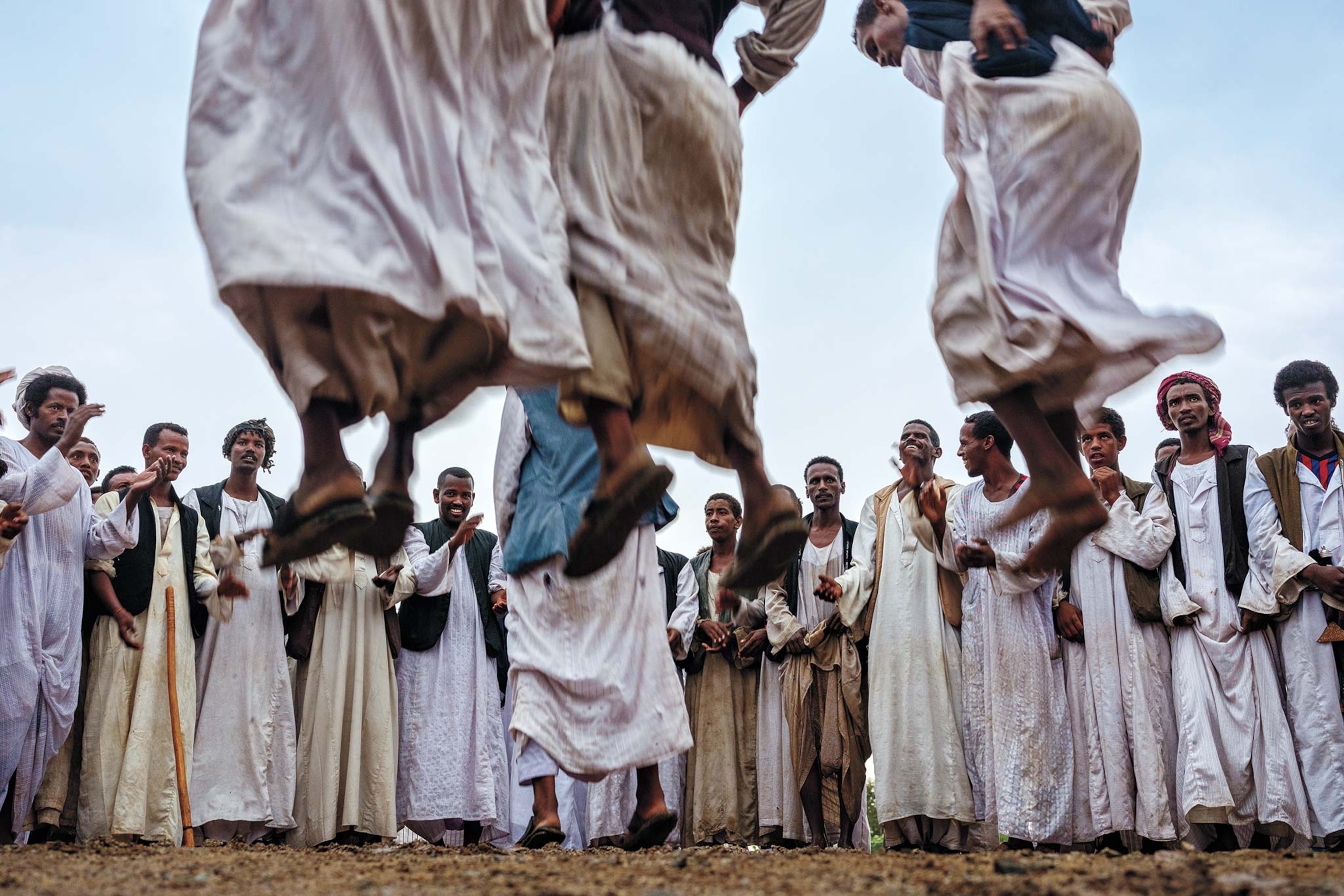 Guests at a wedding are visible behind raised feet of men dancing