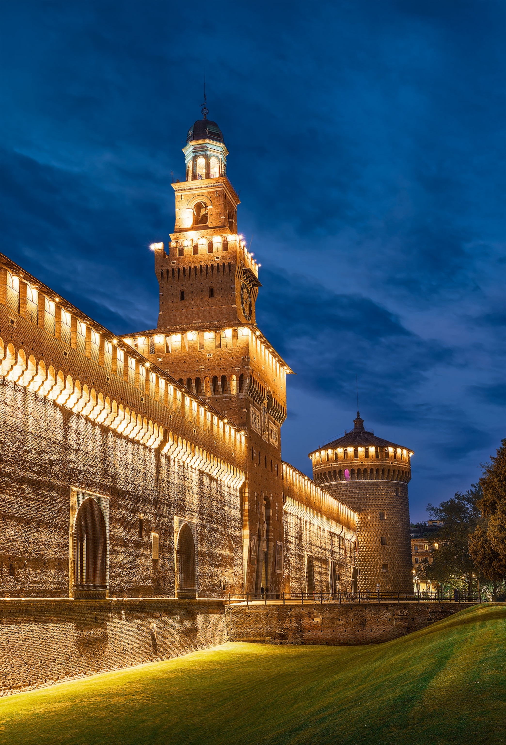 A nighttime view of a castle and its turrets in Milan