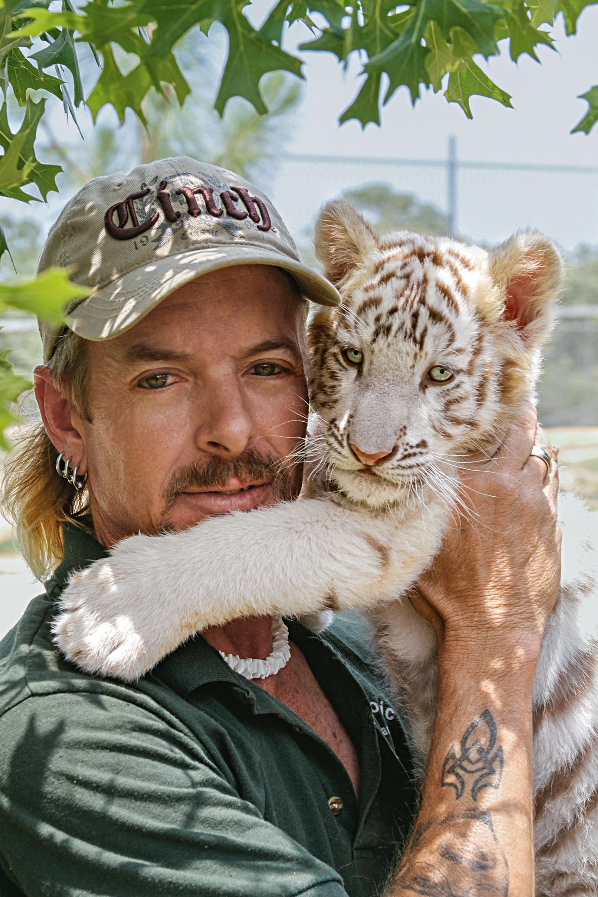 a man holding up a tiger cub next to his face