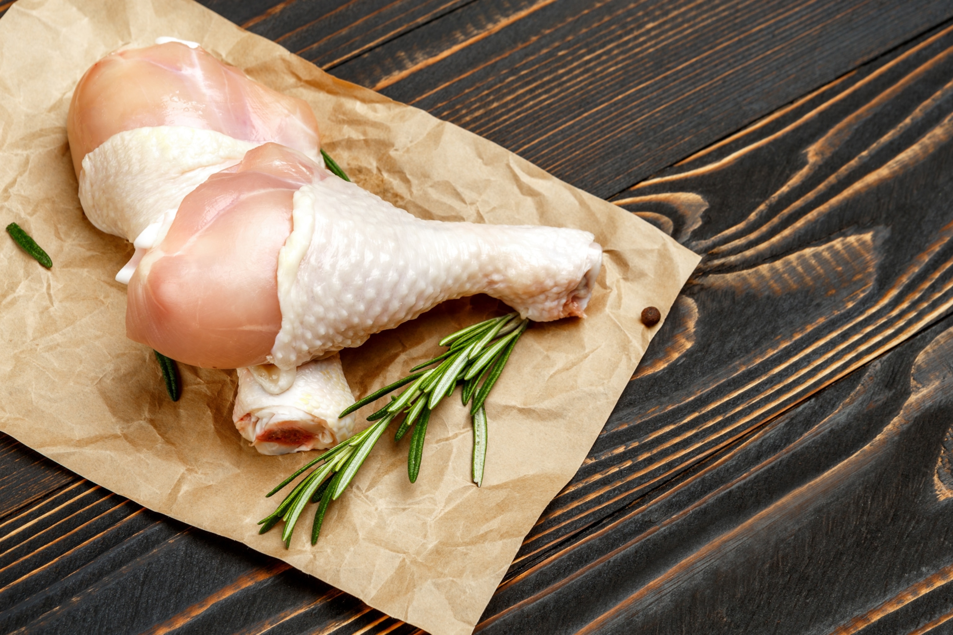 Raw chicken drumsticks on brown butcher paper.