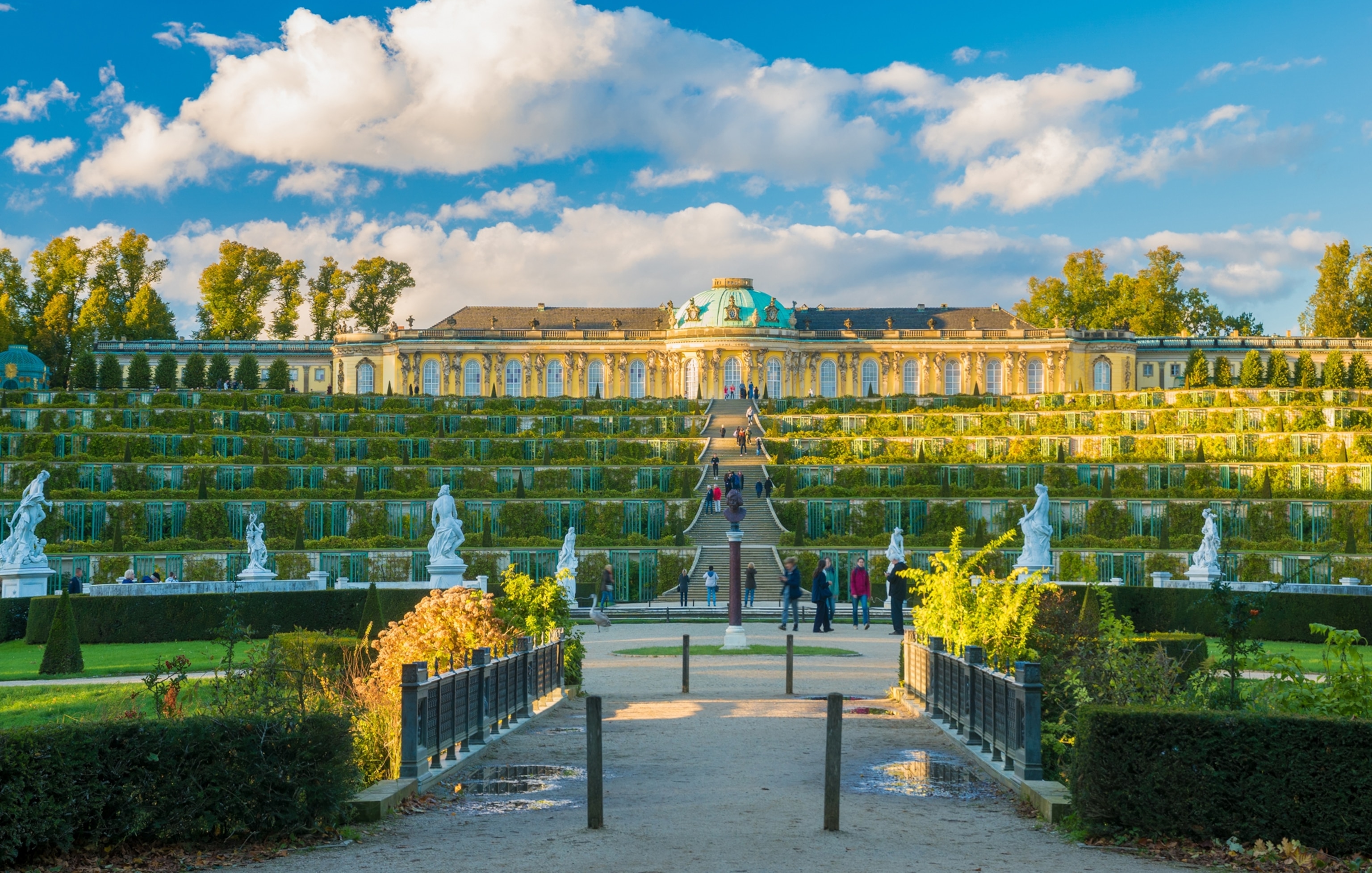 A long elegant building seated atop rows of descending stairs and garden.