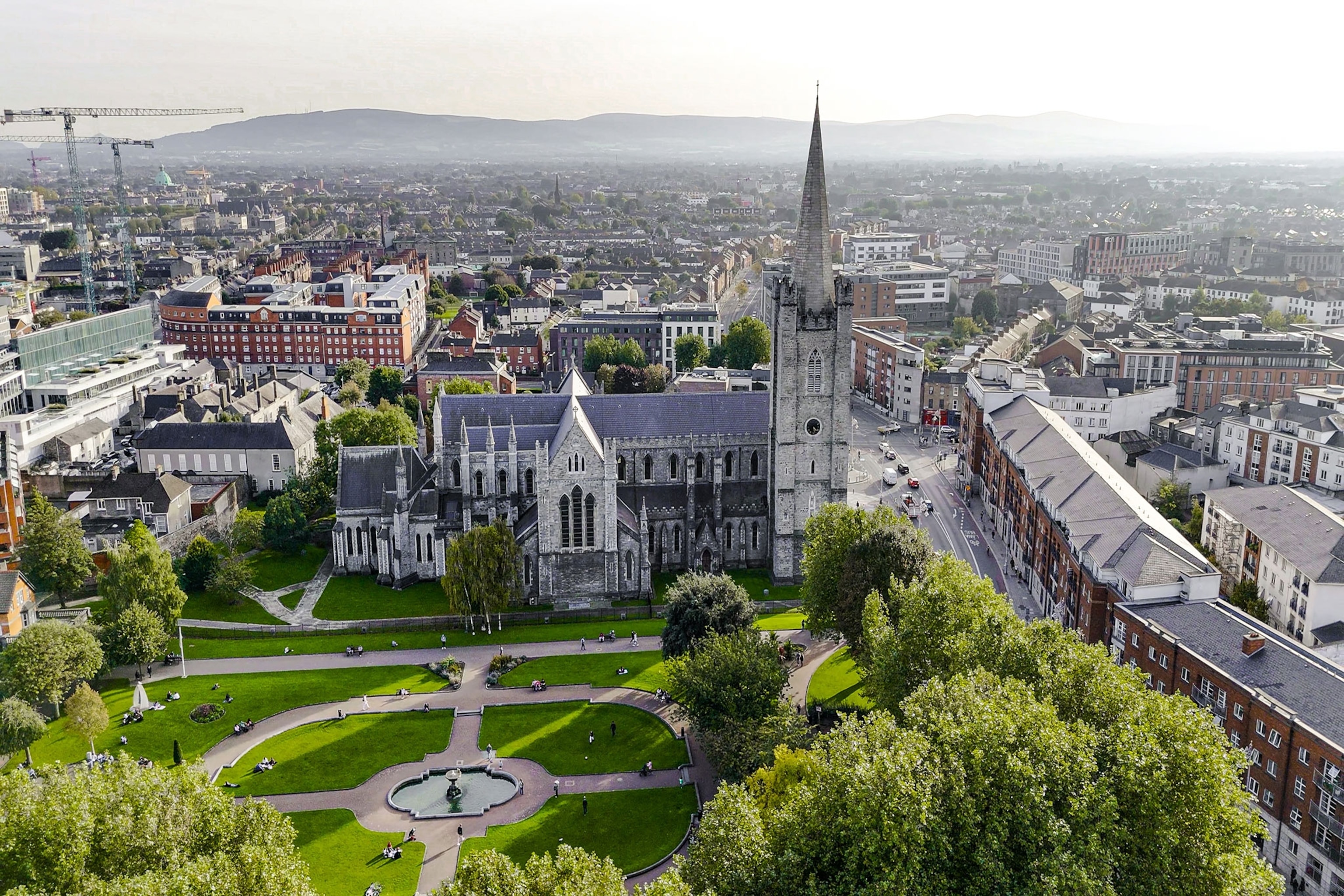 A green park is seen in front of a large cathedral in the city centre.