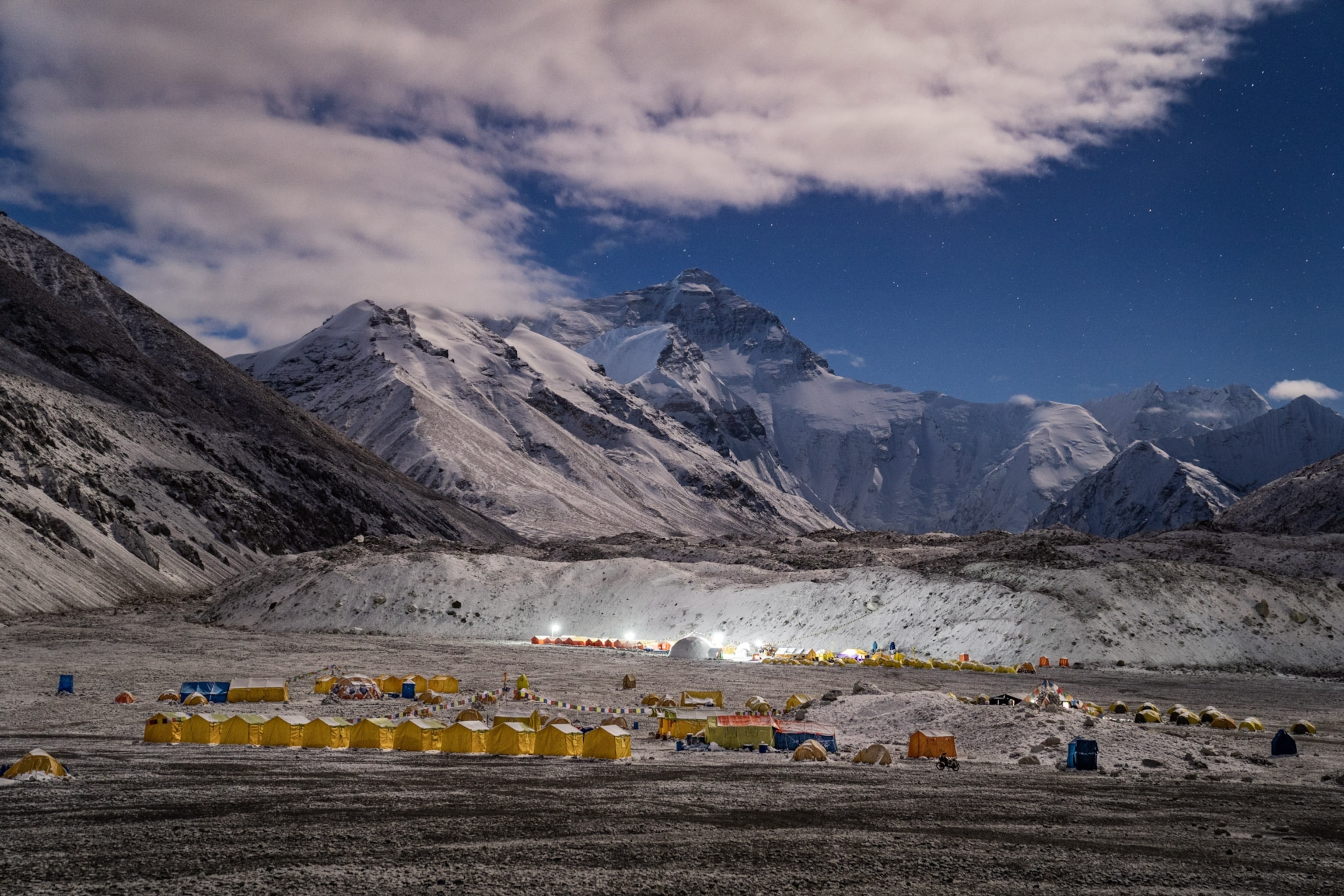 yellow tents lined up in flat area between the peaks of Everest