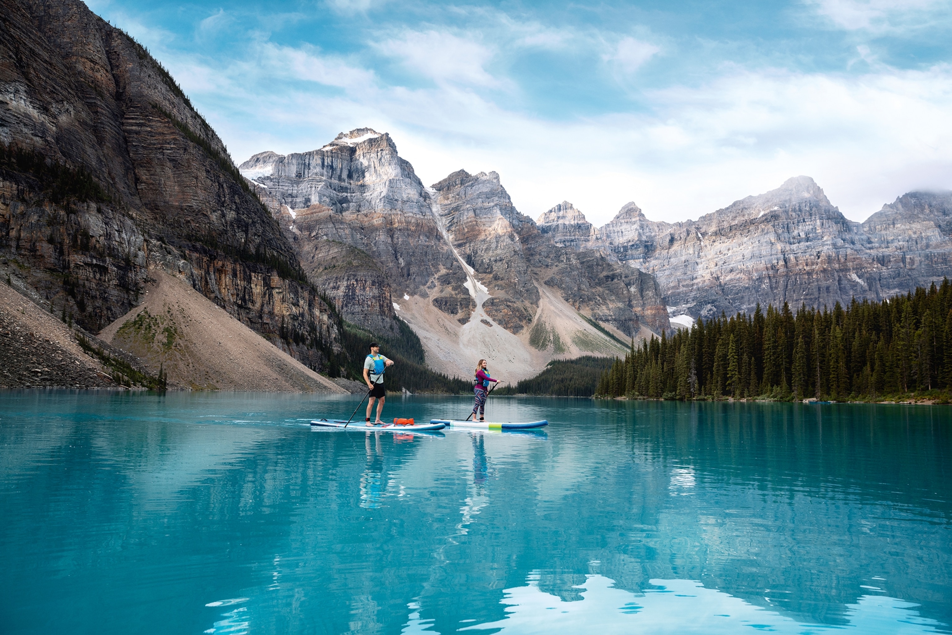 Two people standup paddleboarding on Peyto Lake, in front of mountains in Banff National Park.