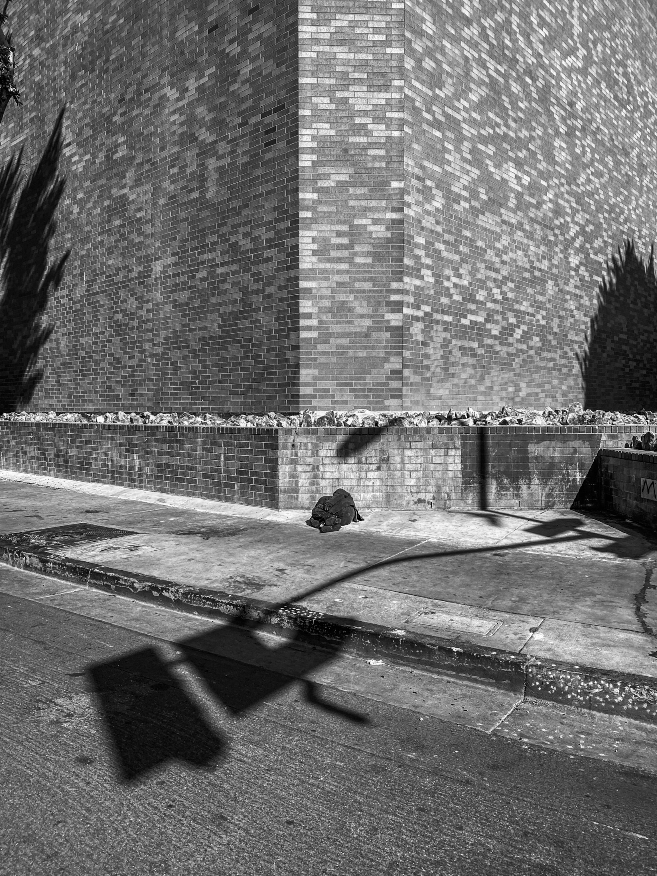 a homeless person covered with a blanket sitting against a wall