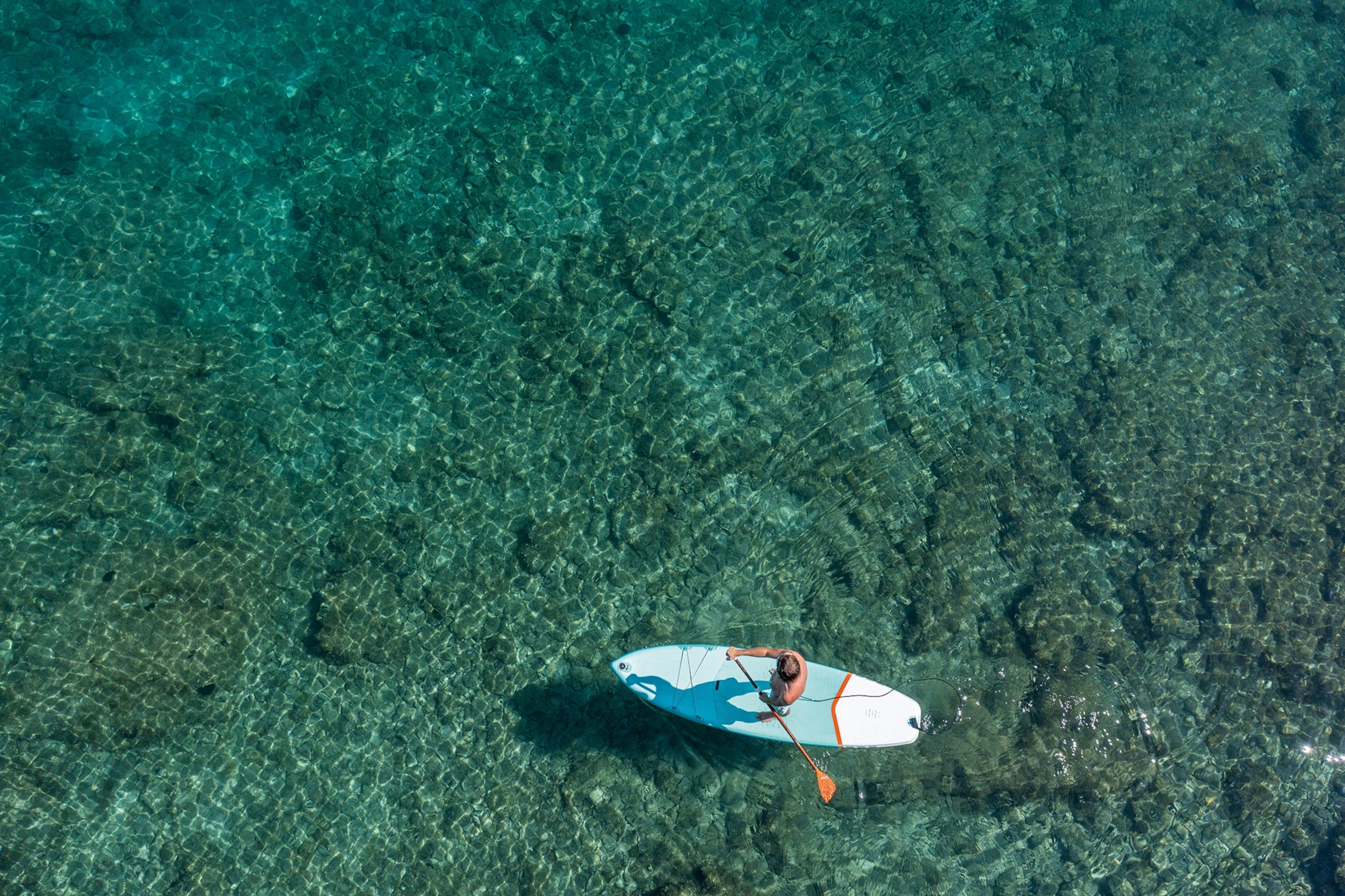 Arial view of a paddleboarder making their way over a reef in Croatia.