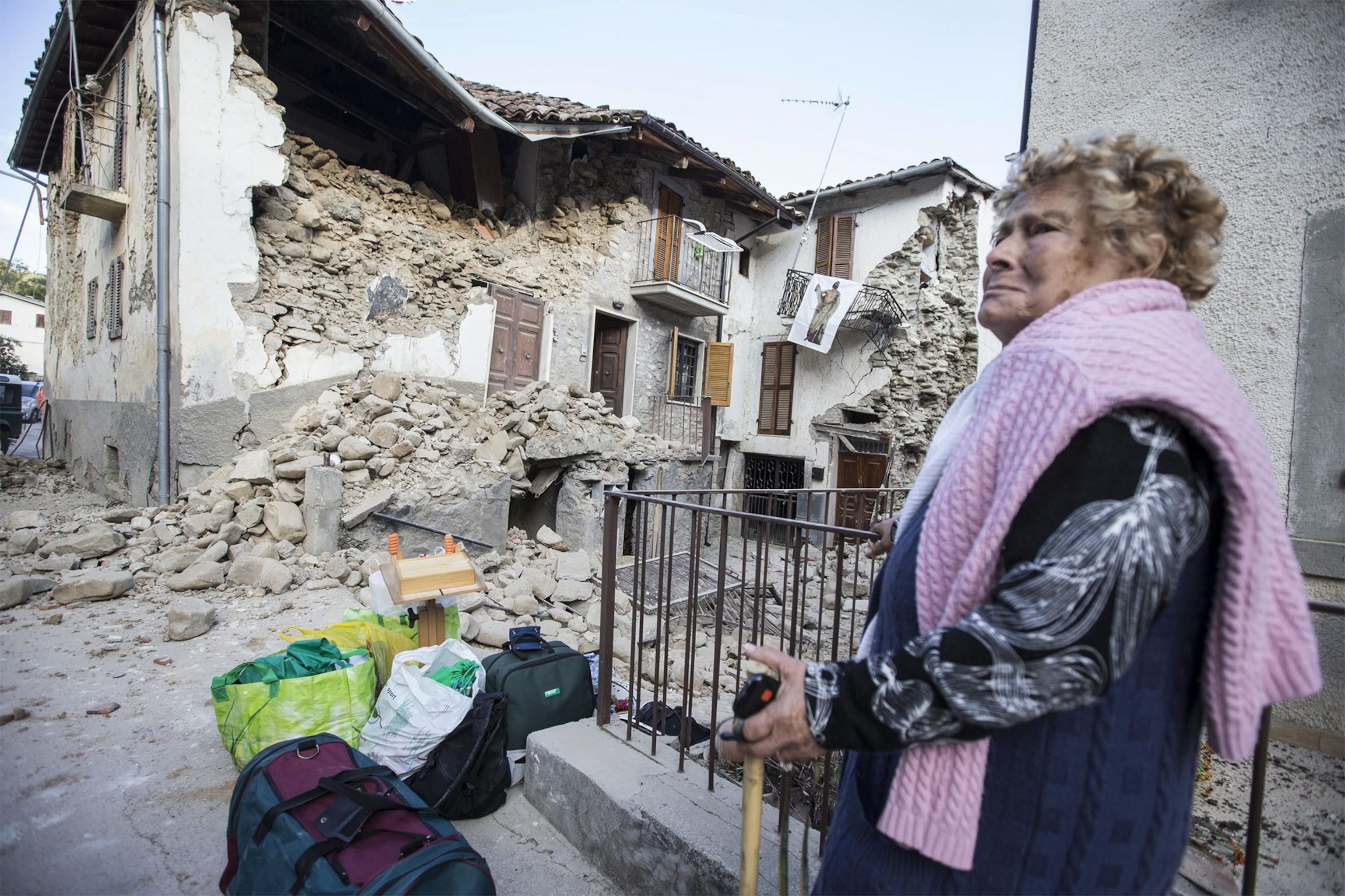 a woman looking at damaged houses after an earthquake in Italy