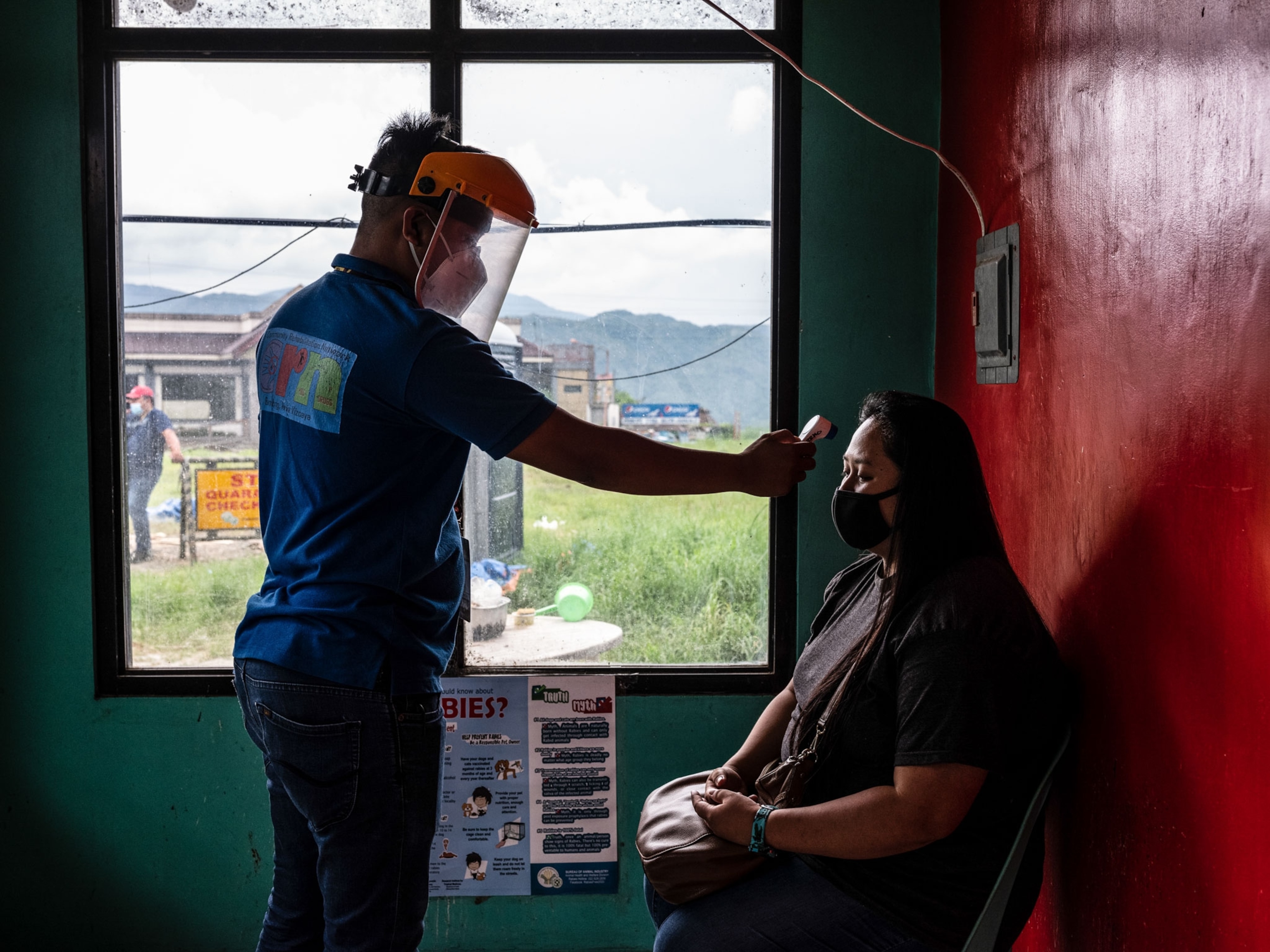 a man taking a women's temperature in the Philippines
