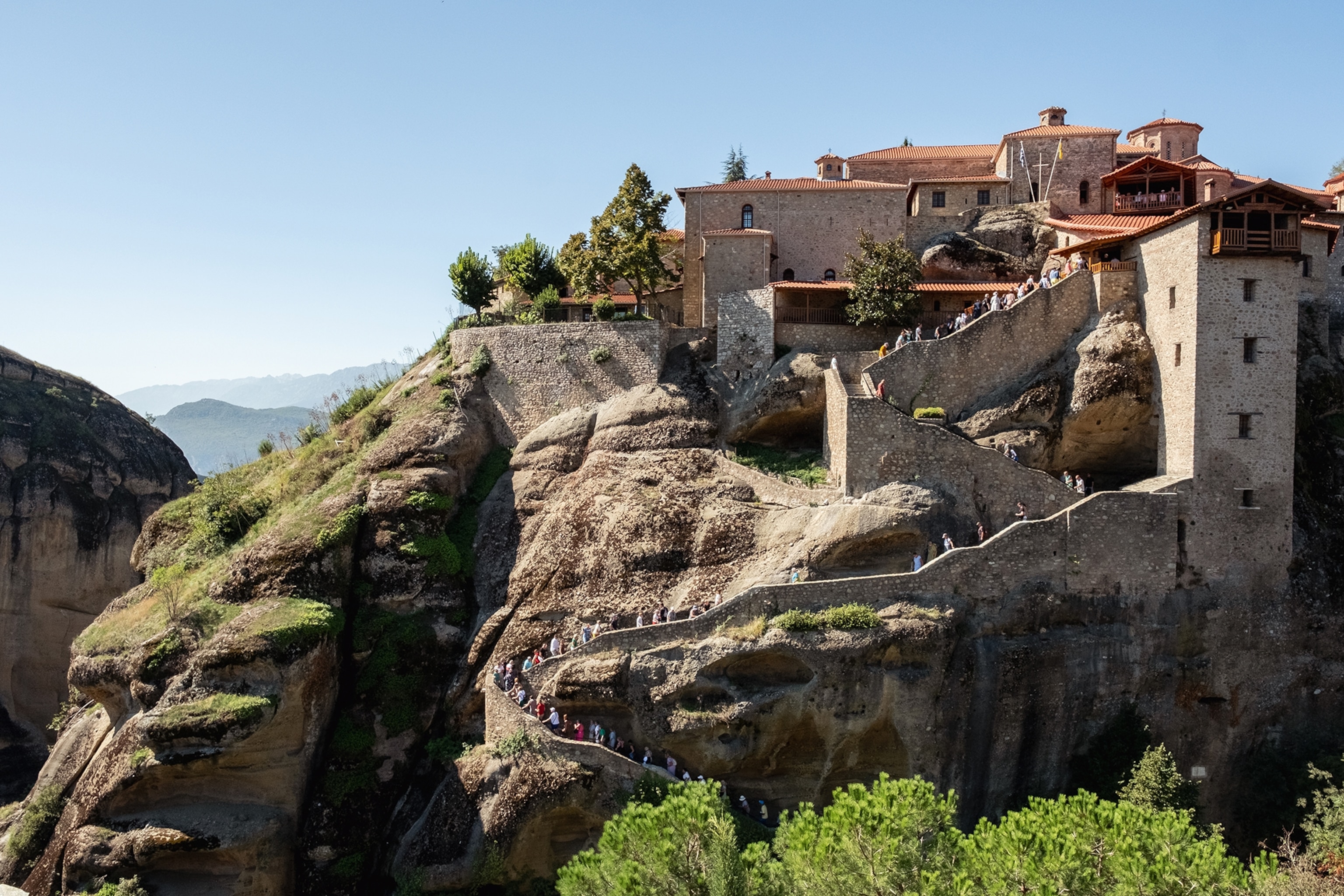 A view onto a stone wall with a sloping walkway up to the monastery sitting on top.