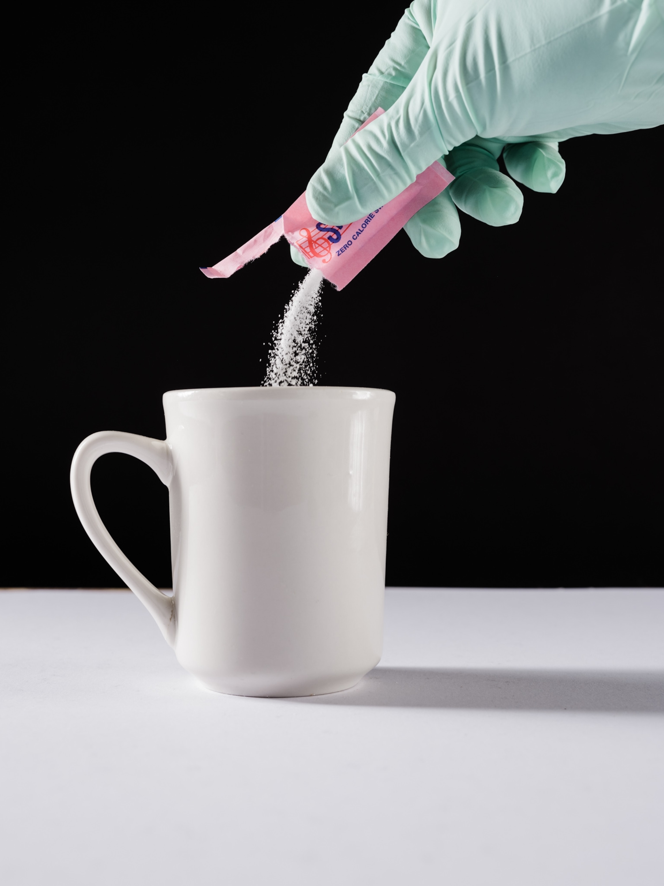 Studio shoot with black backdrop showing packets of artificial sweeteners