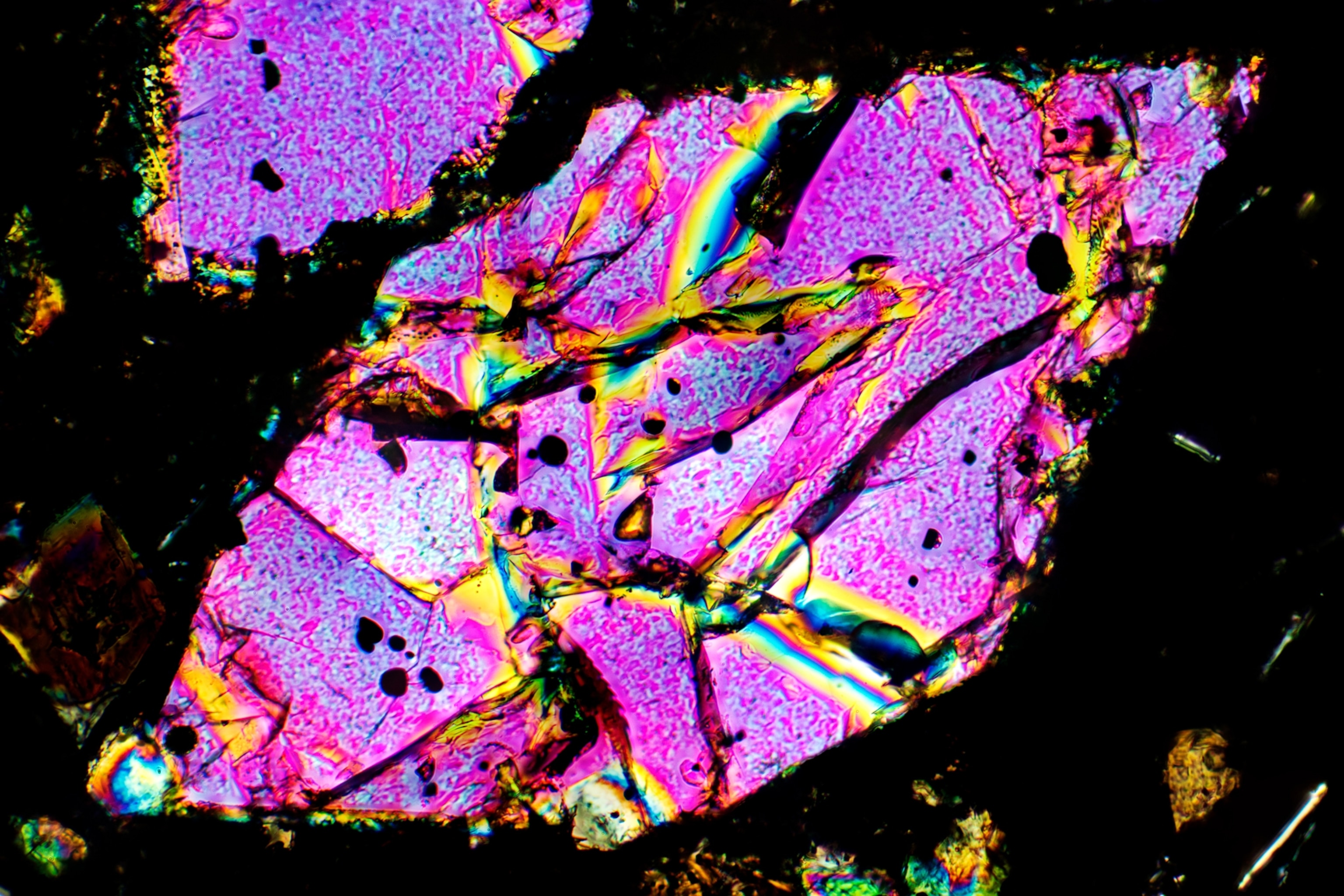 A diamond shaped, pink iridescent sample of olivine.