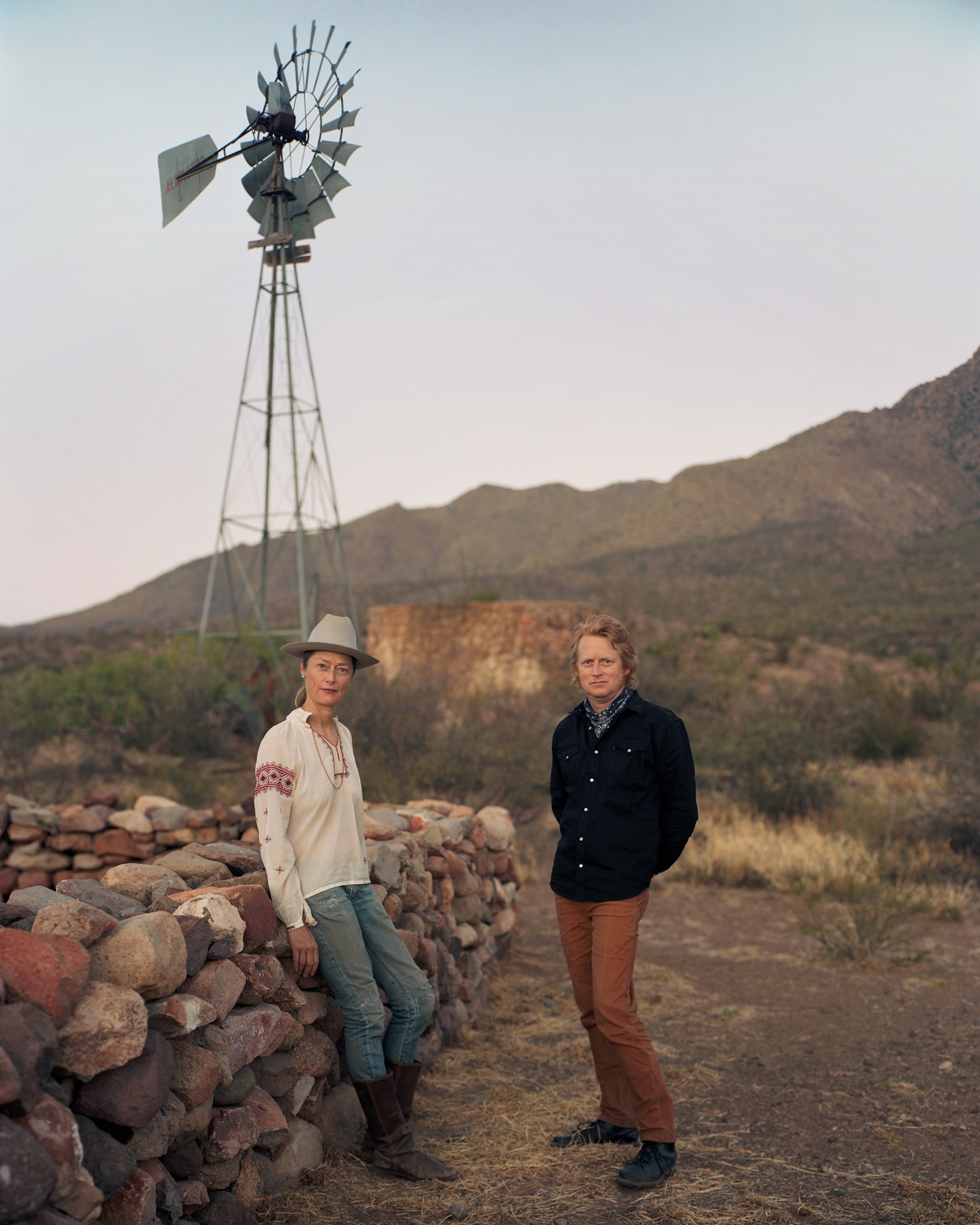 Picture of woman and man next to stone wall under windmill.
