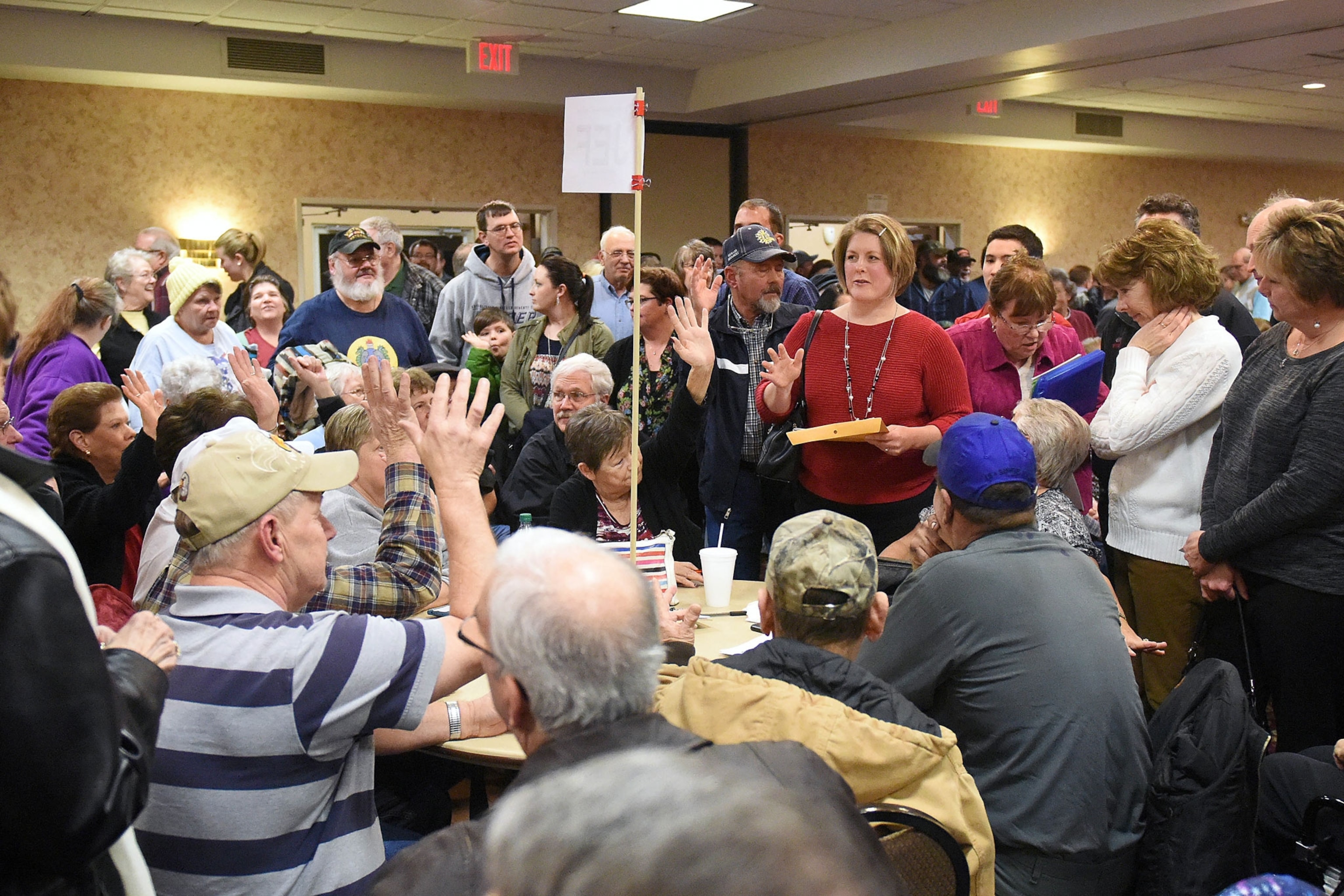 people raising their hands during a local Republican Party caucus in Madison Iowa