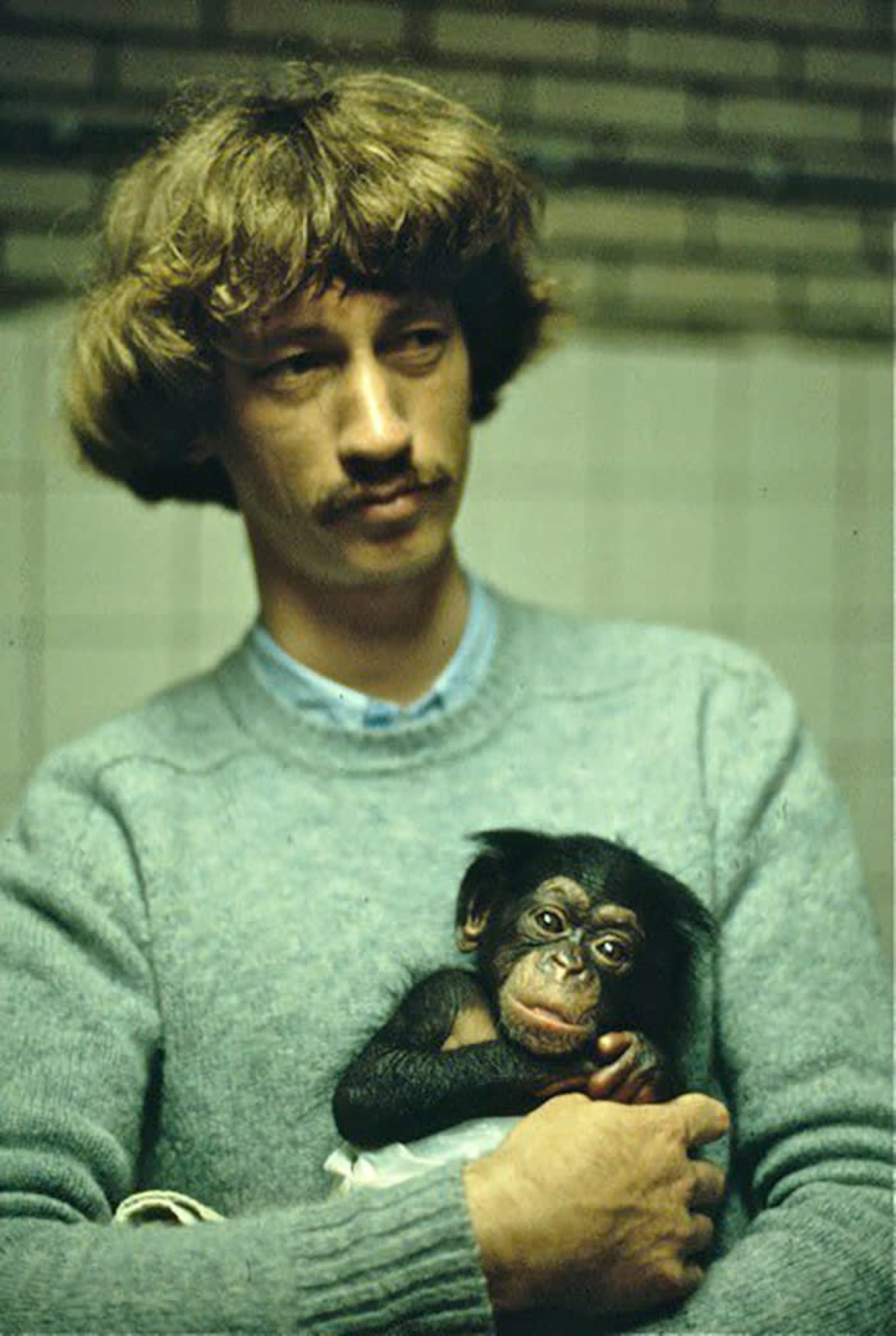 Picture of a young Frans de Waal holding a baby chimp in his arms.