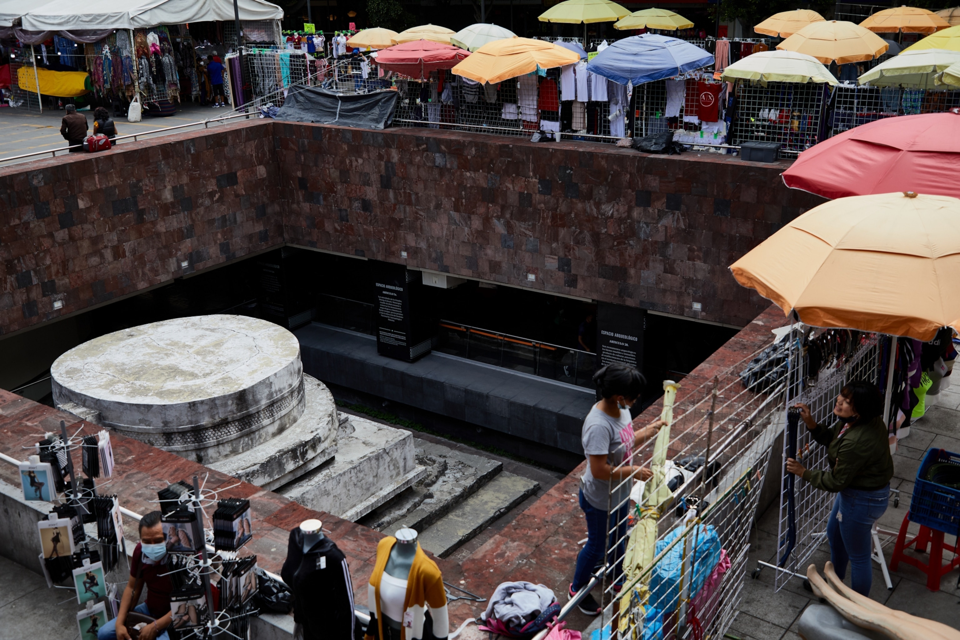 The pyramid of Ehecatl, the smallest archaeological site in Mexico, located in the Metro station "Pino Suarez" in Mexico City and surrounded by vendors above.