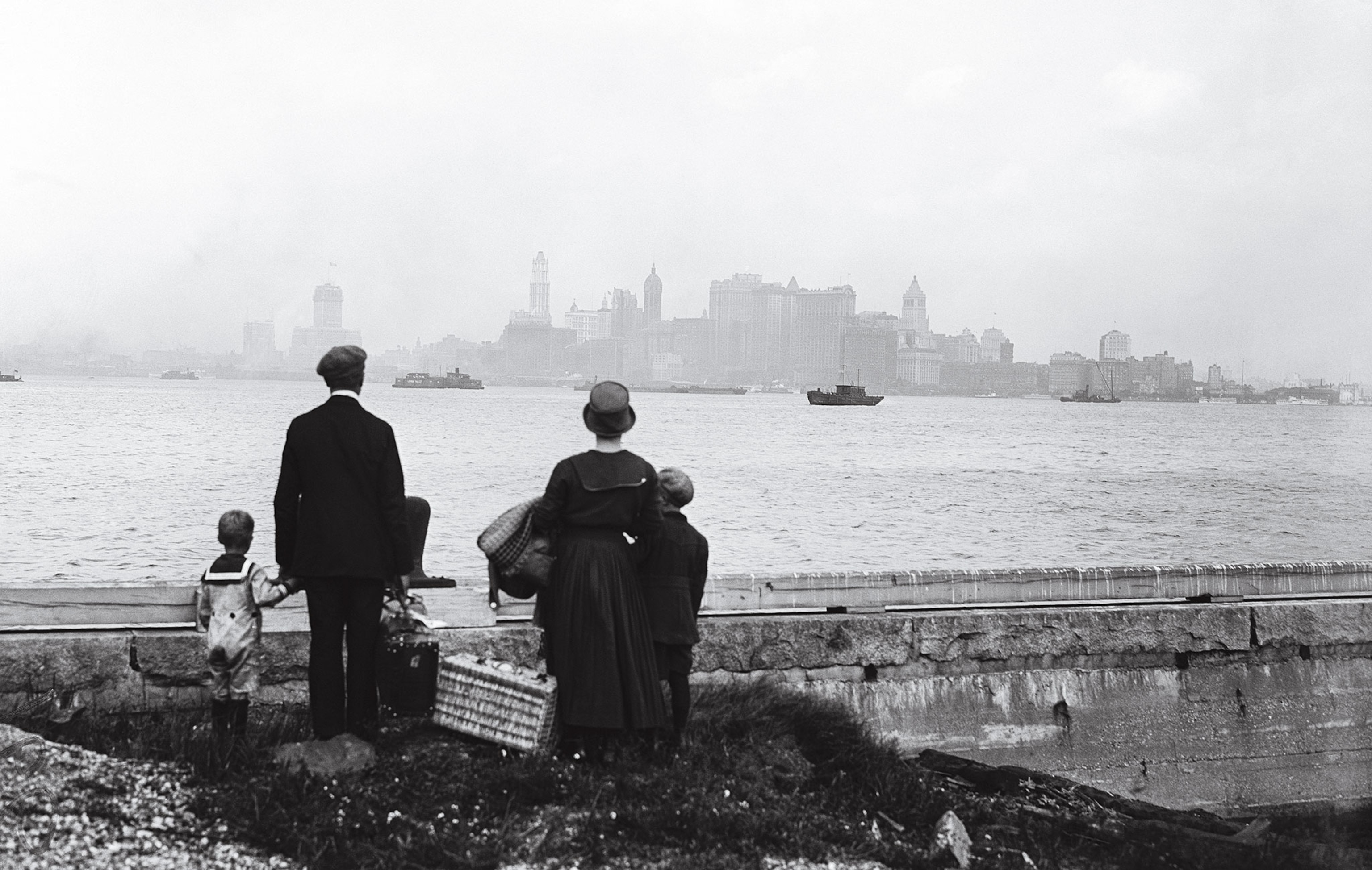 This unidentified family, gazing from Ellis Island to Manhattan, in a black-and-white photograph
