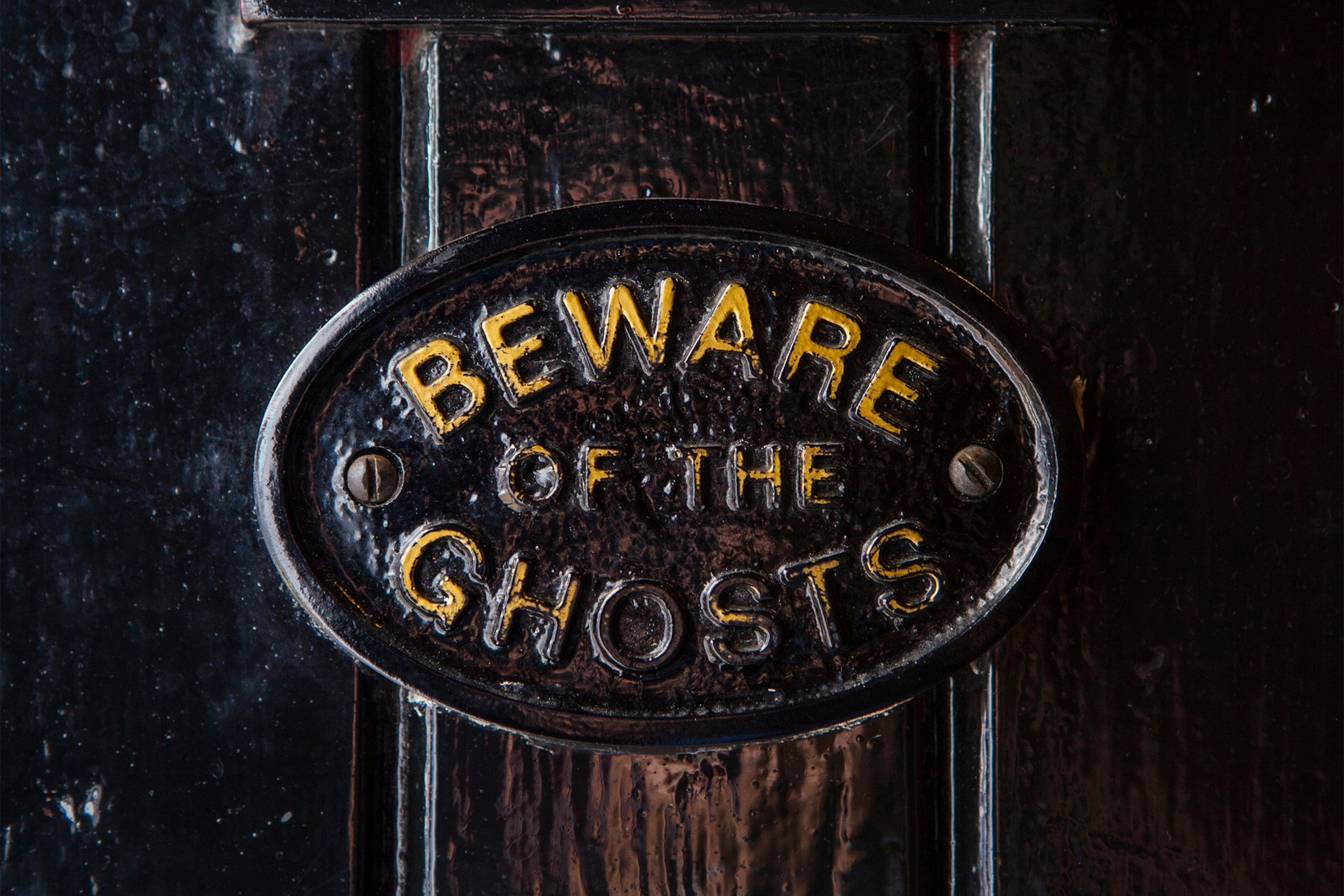 a close-up of a beware of the ghosts sign at a pub