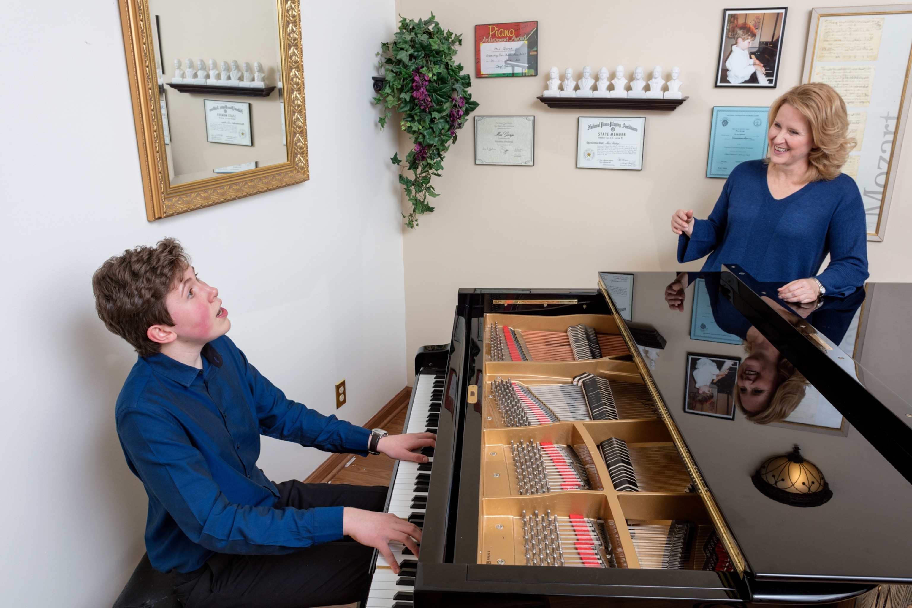 a pre-teen boy prodigy playing piano as his mother smiles at him