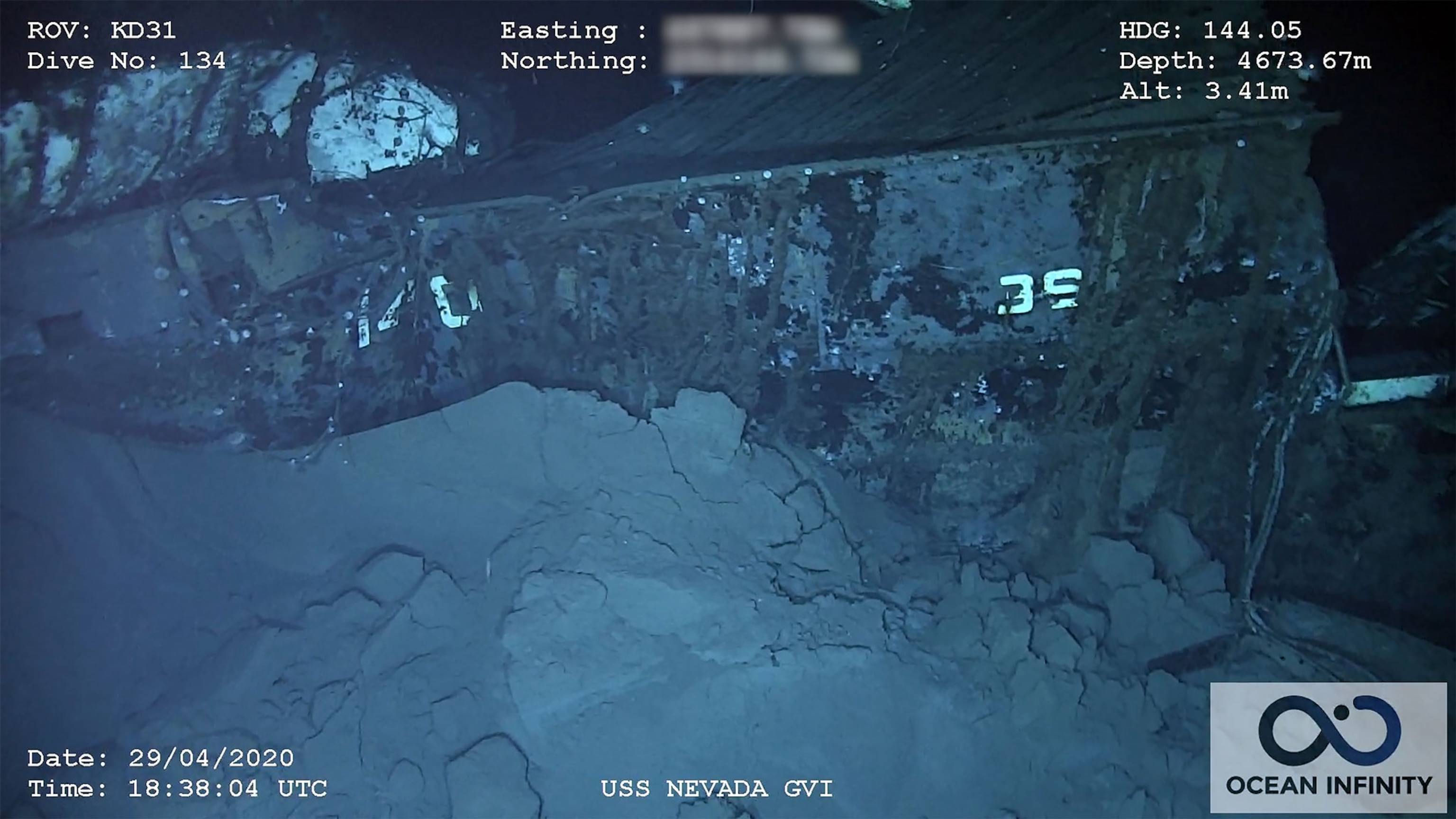 An underwater picture of the hull of a ship half buried in mud