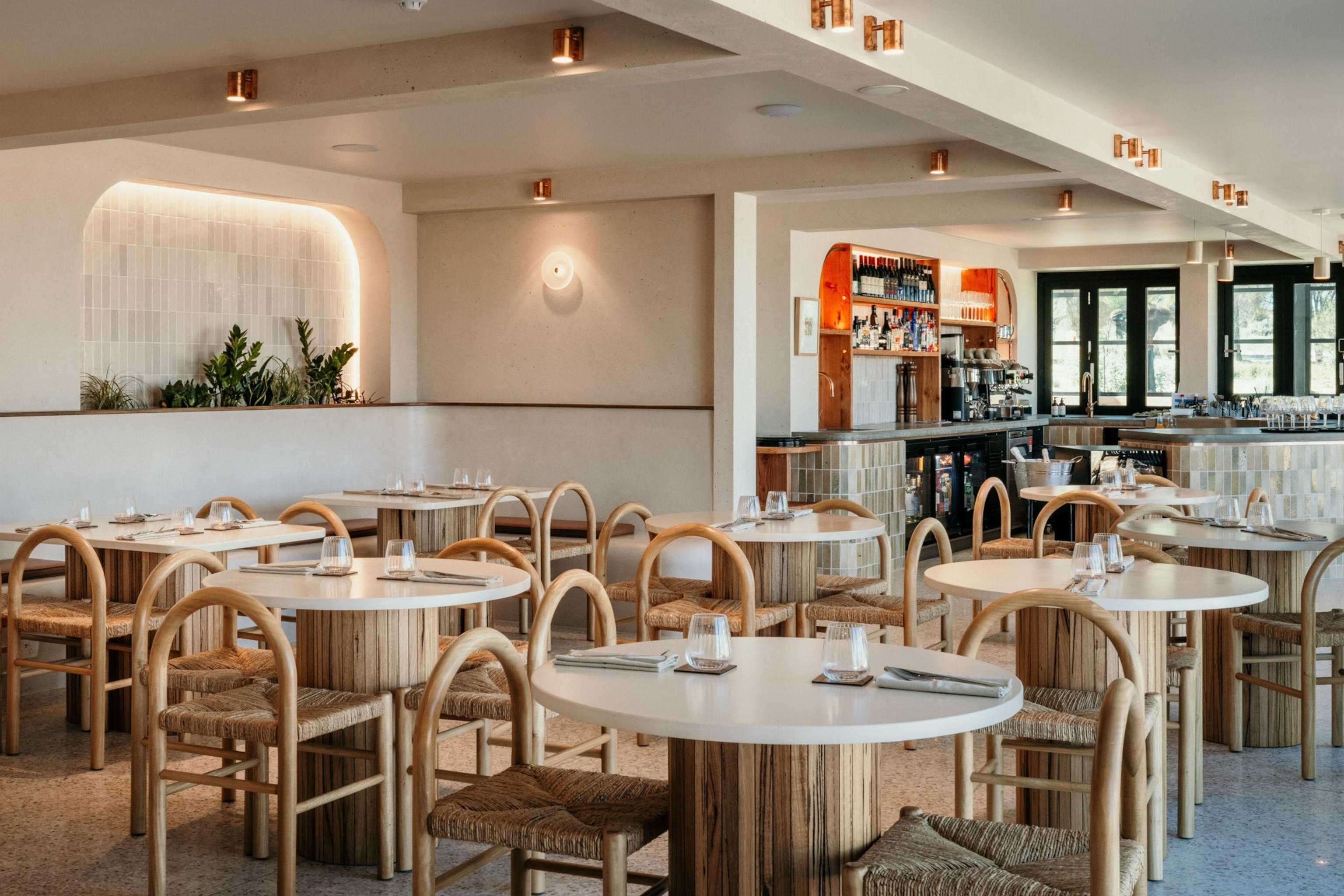 Inside dining space with a modern feel with white walls and wooden chairs.