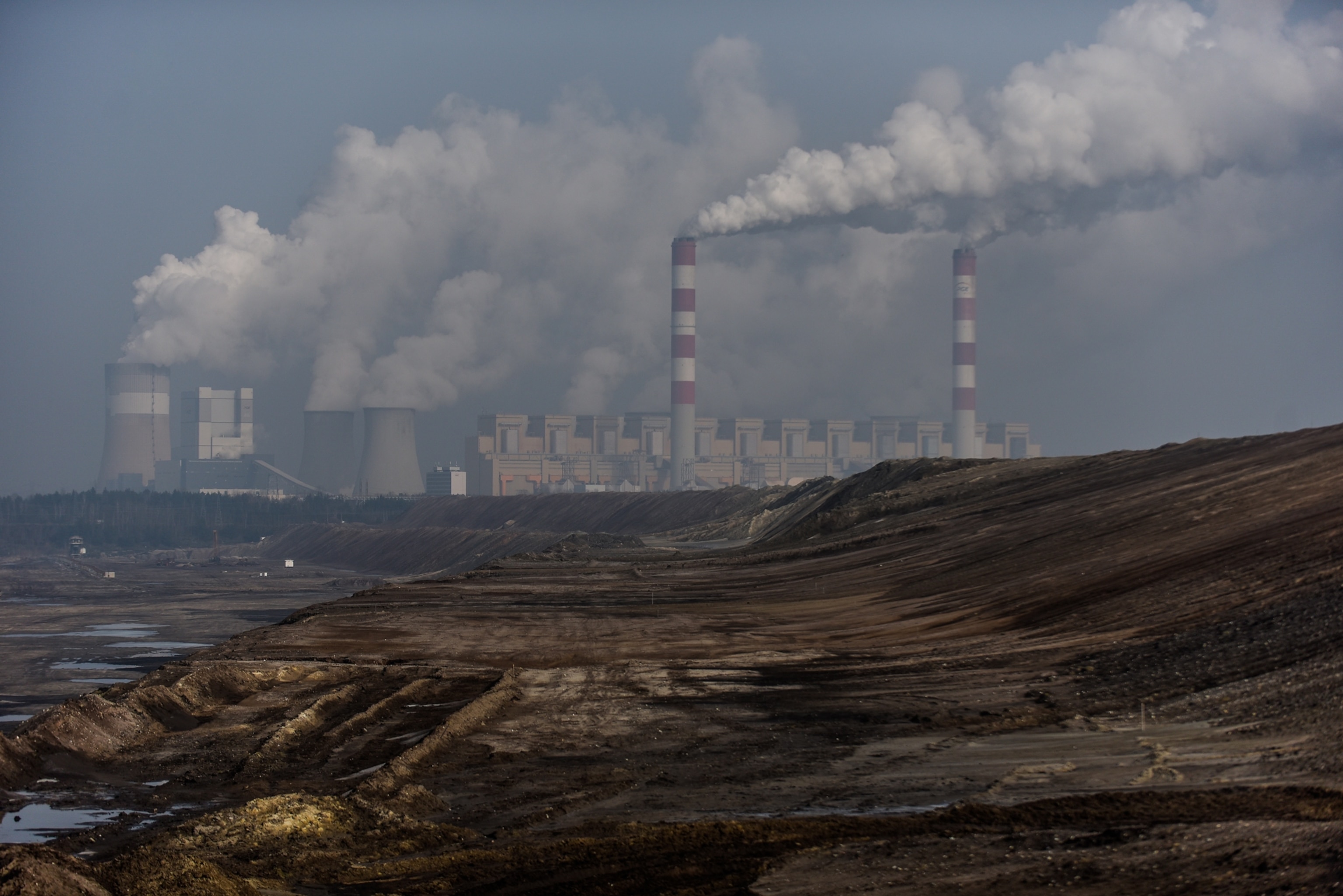 smoke rising out of red and white stripped coal stacks with some wider white water vapor stacks near by