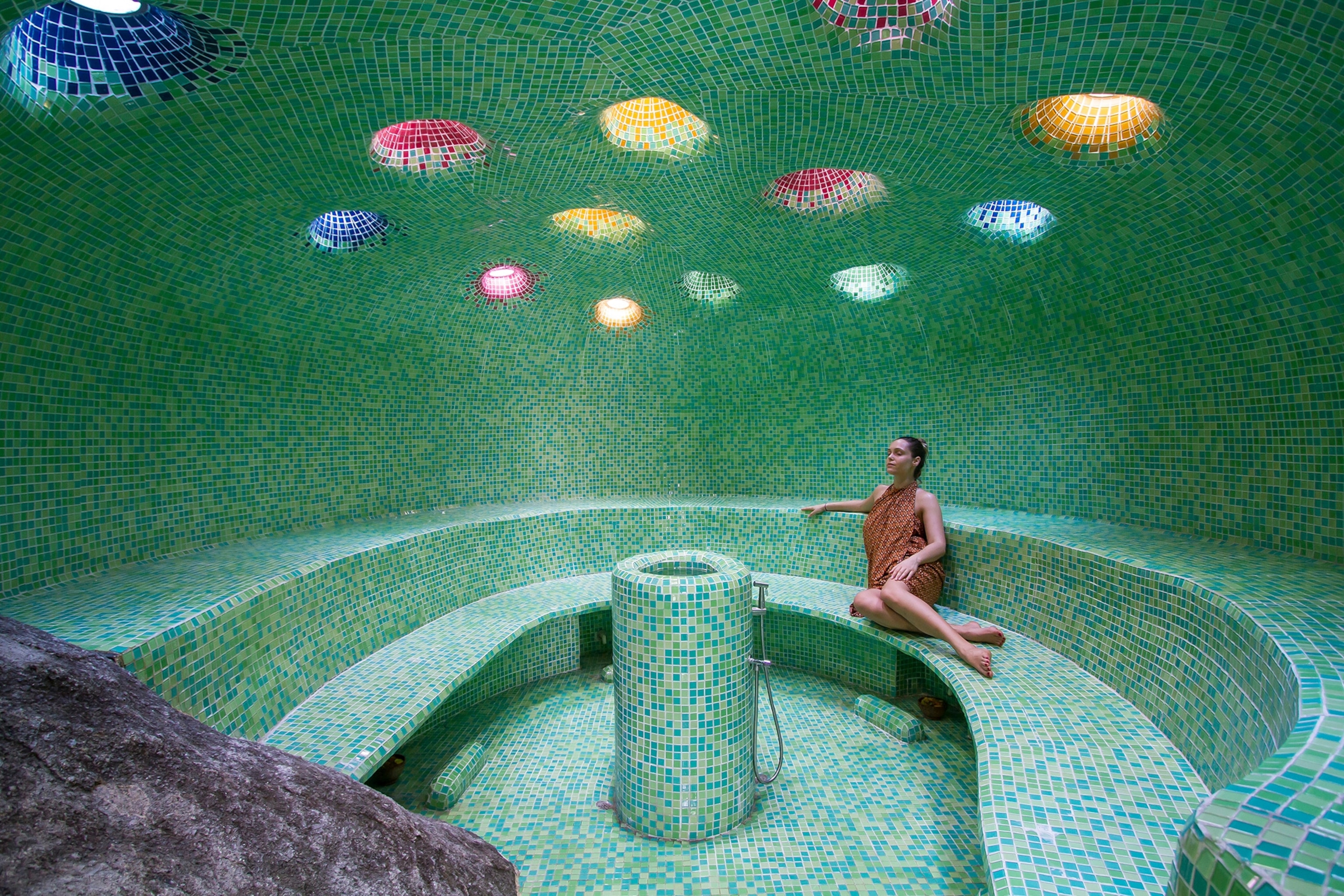 A guest sits in a turquoise tiled steam cavern at Kamalaya resort.