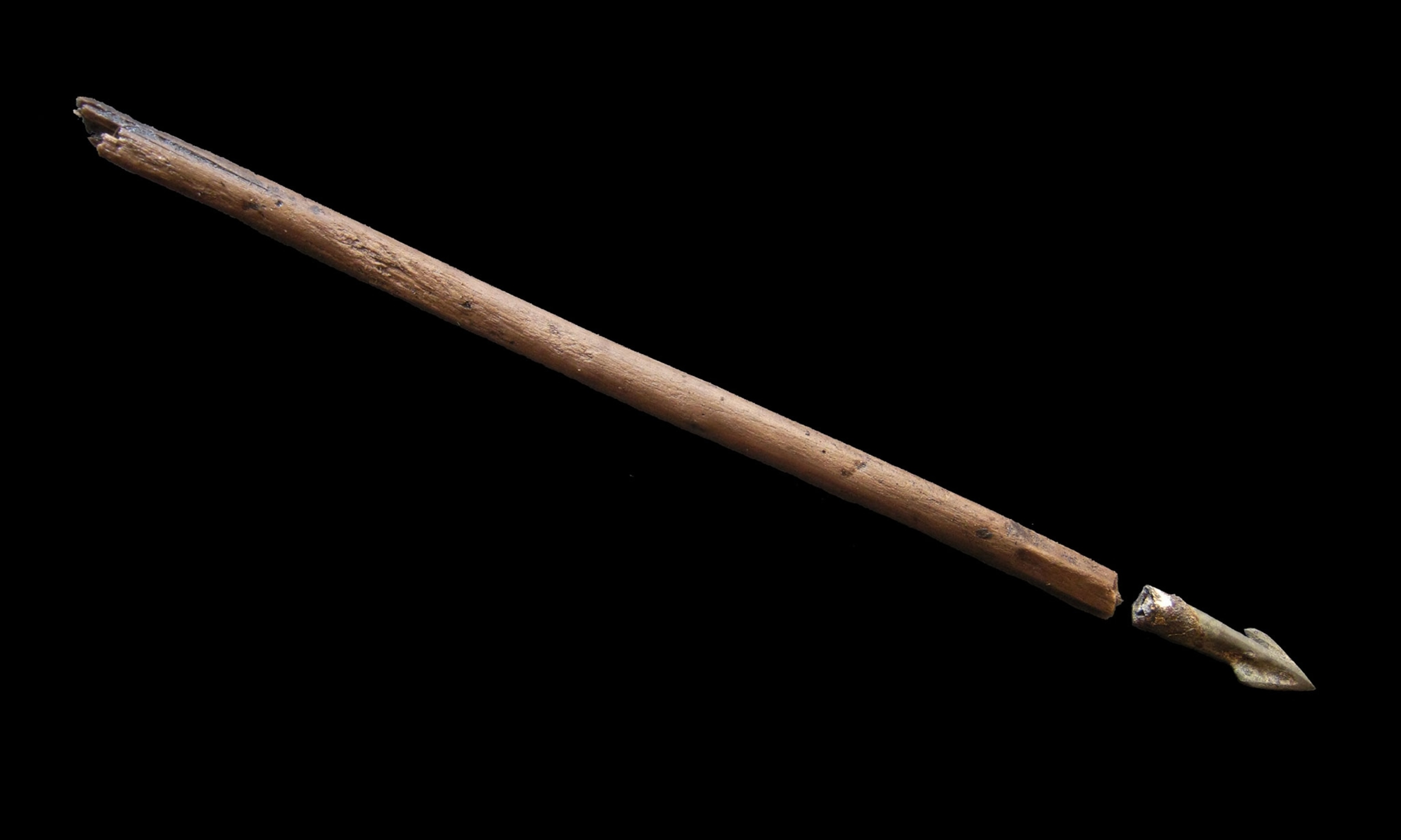 An arrow shaft and arrow head placed in front of a black background.