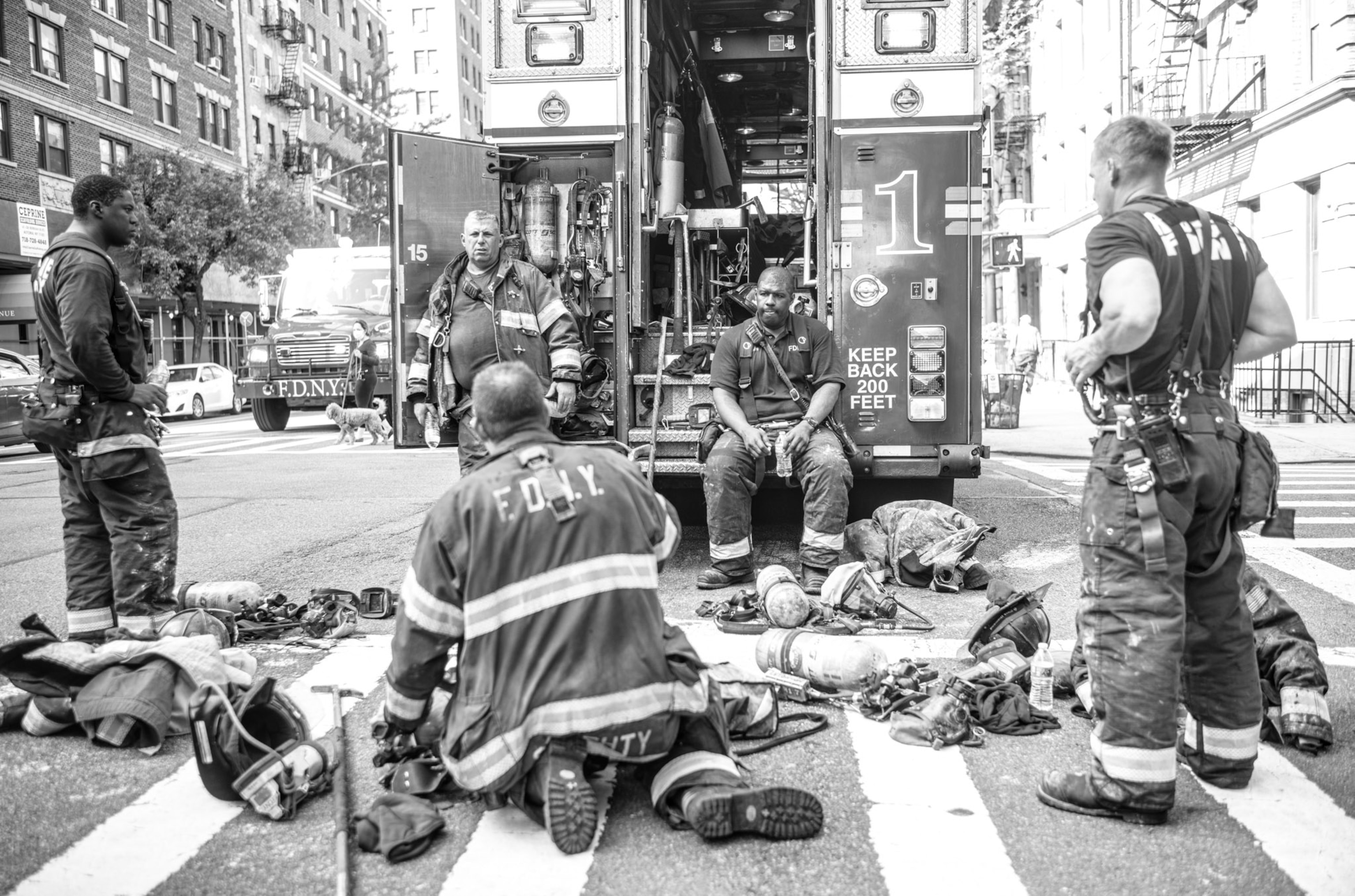 firefighters sitting and standing behind a fire truck - equipment scattered around them