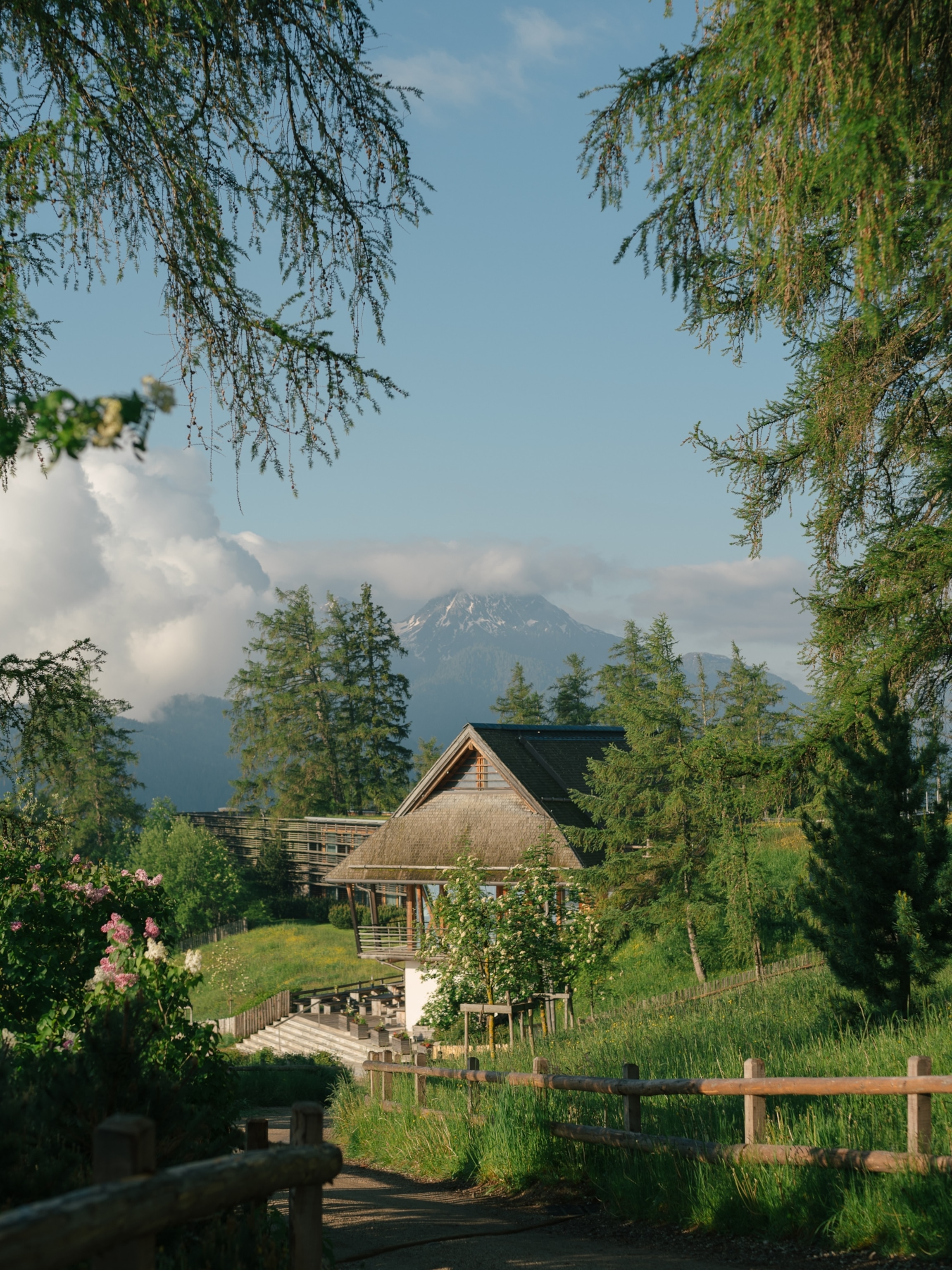 A distant view of a hotel, surrounded by trees flowers and greenery.