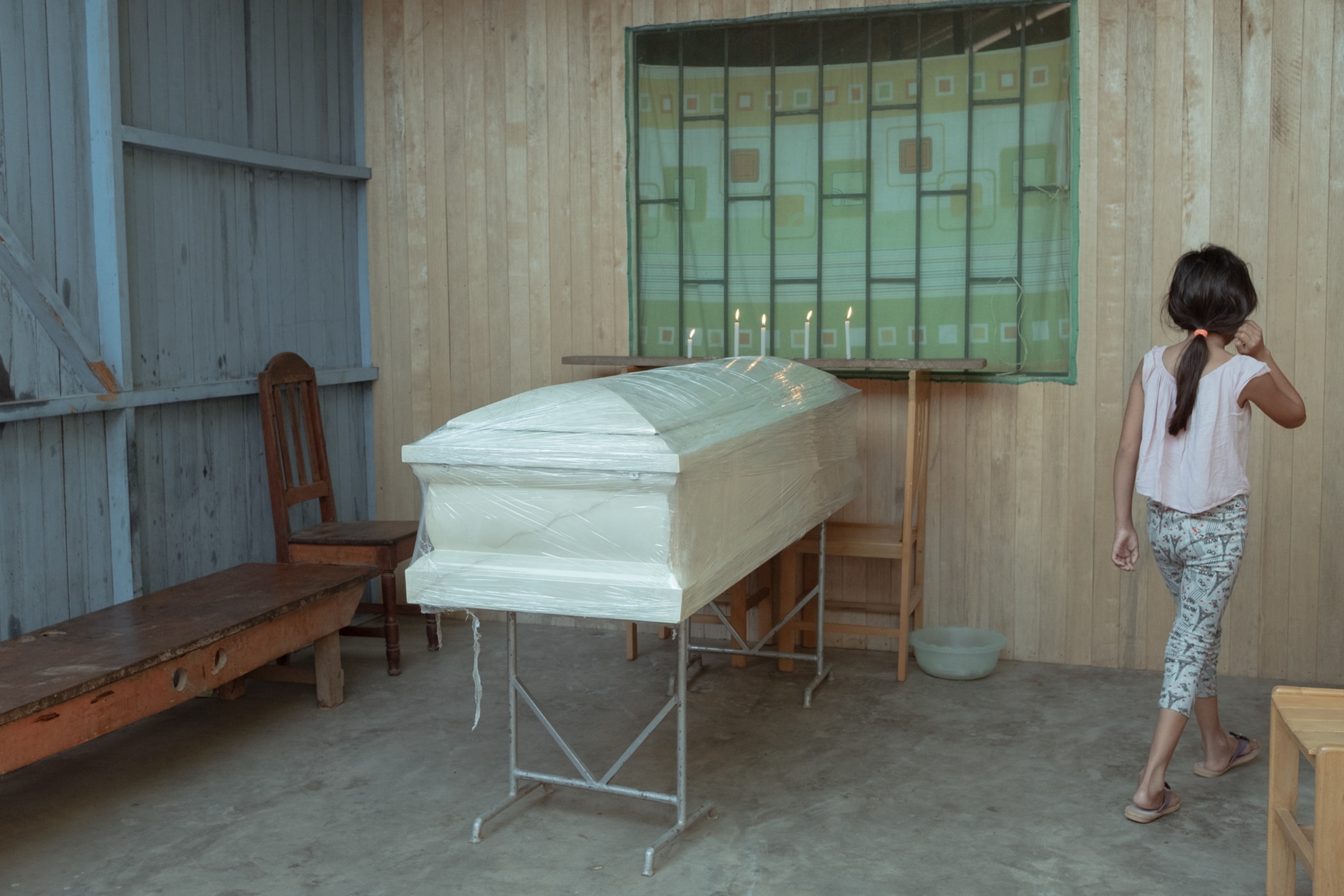 a girl walks past a casket in Peru