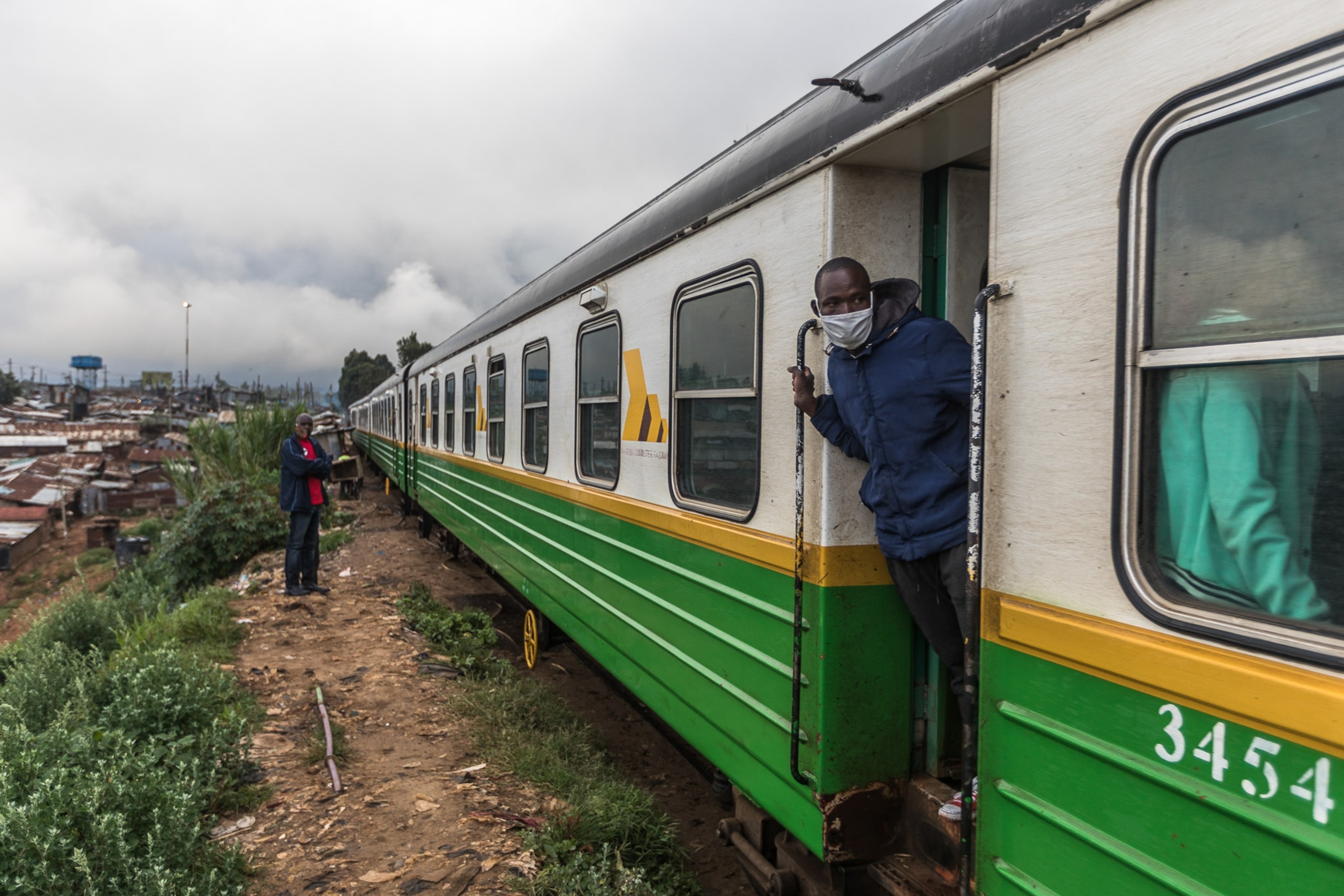 a person standing in the doorway of a green and white train car